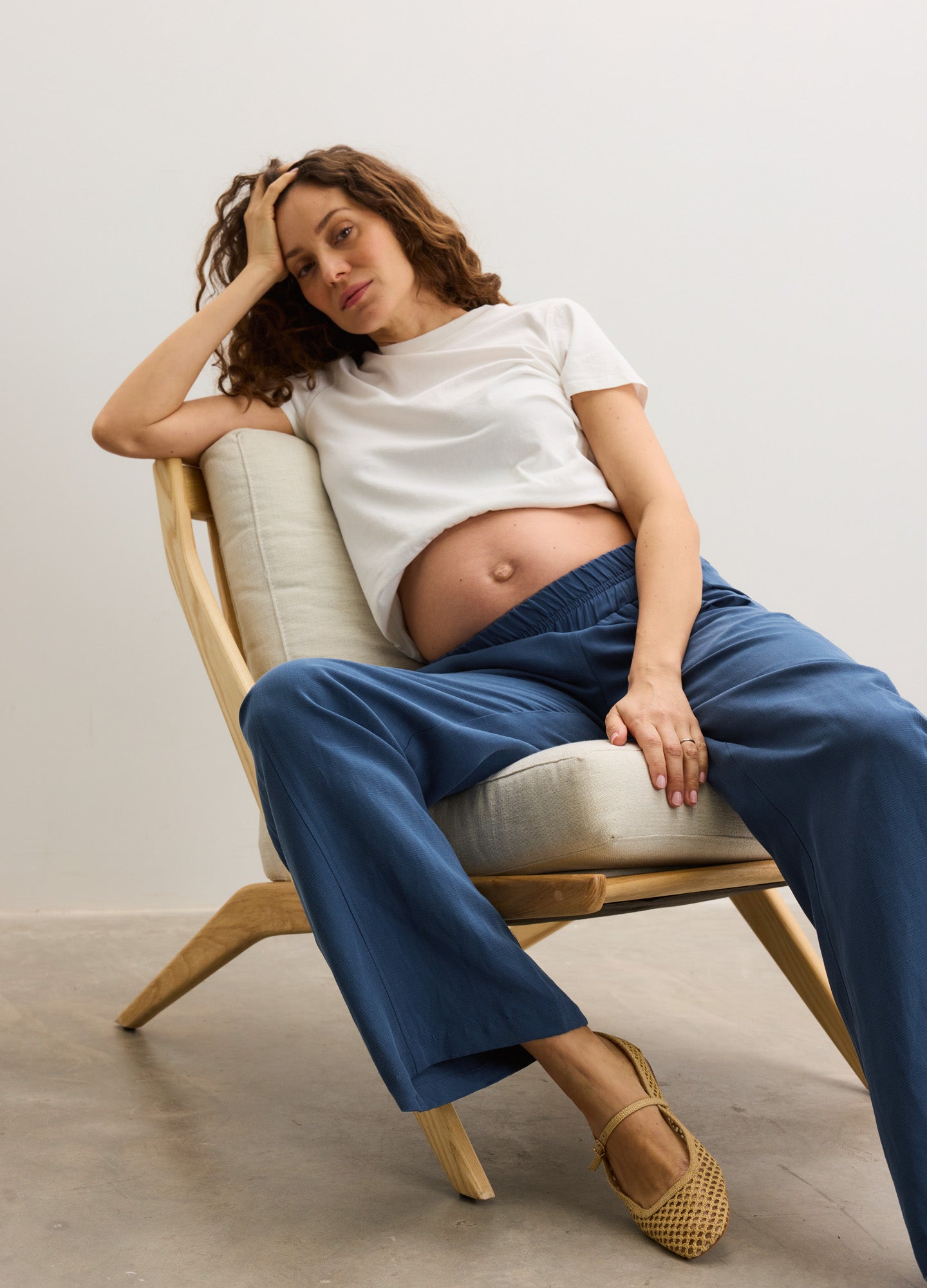 Maternity pants in soft blue with a relaxed straight-leg fit, styled with a white cropped tee and beige flats.