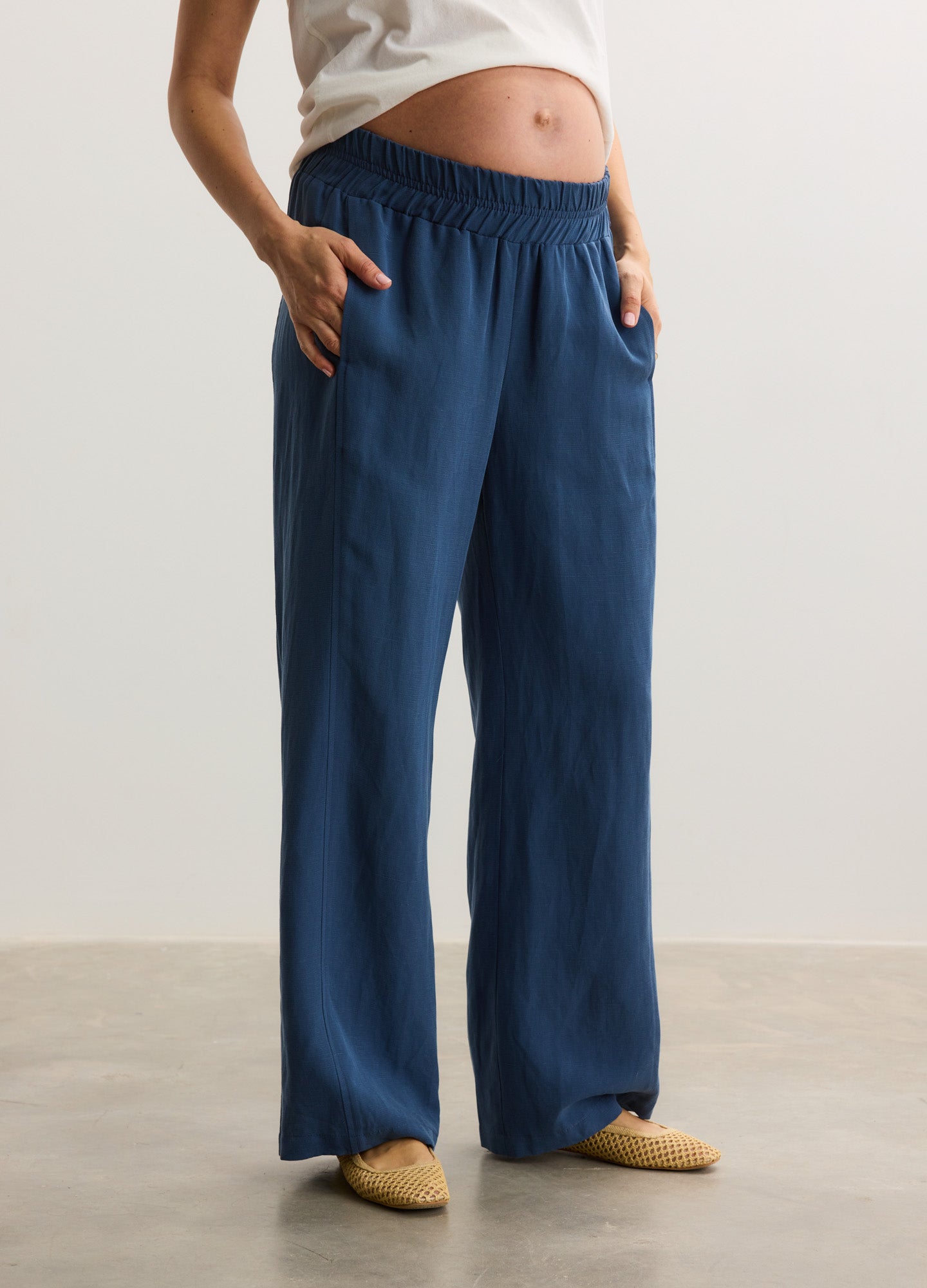 Navy blue maternity pants with elastic waistband and wide legs, worn by pregnant model.