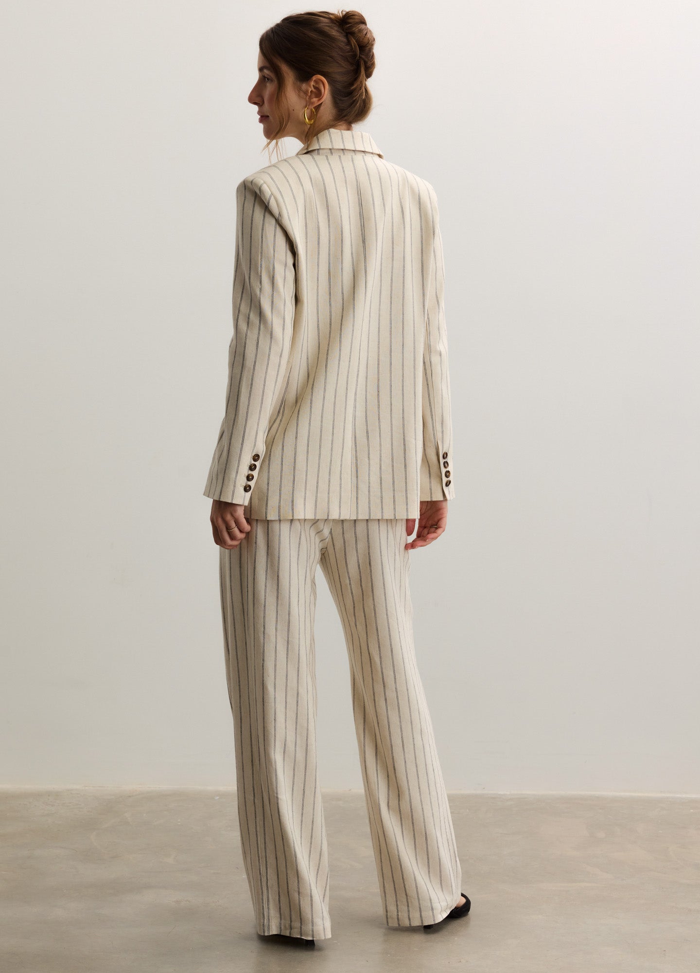 Beige pinstripe maternity pants with a relaxed wide-leg fit, designed for pregnant wear with extra room at the waist.