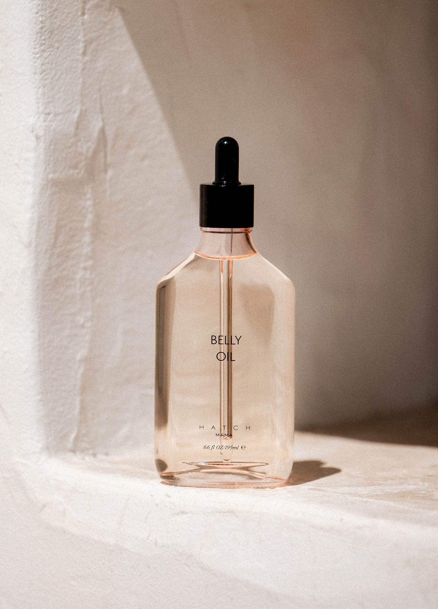 Belly Oil - Clear glass bottle of maternity belly oil with soft pink liquid, designed for pregnancy, nursing, and postpartum care next.