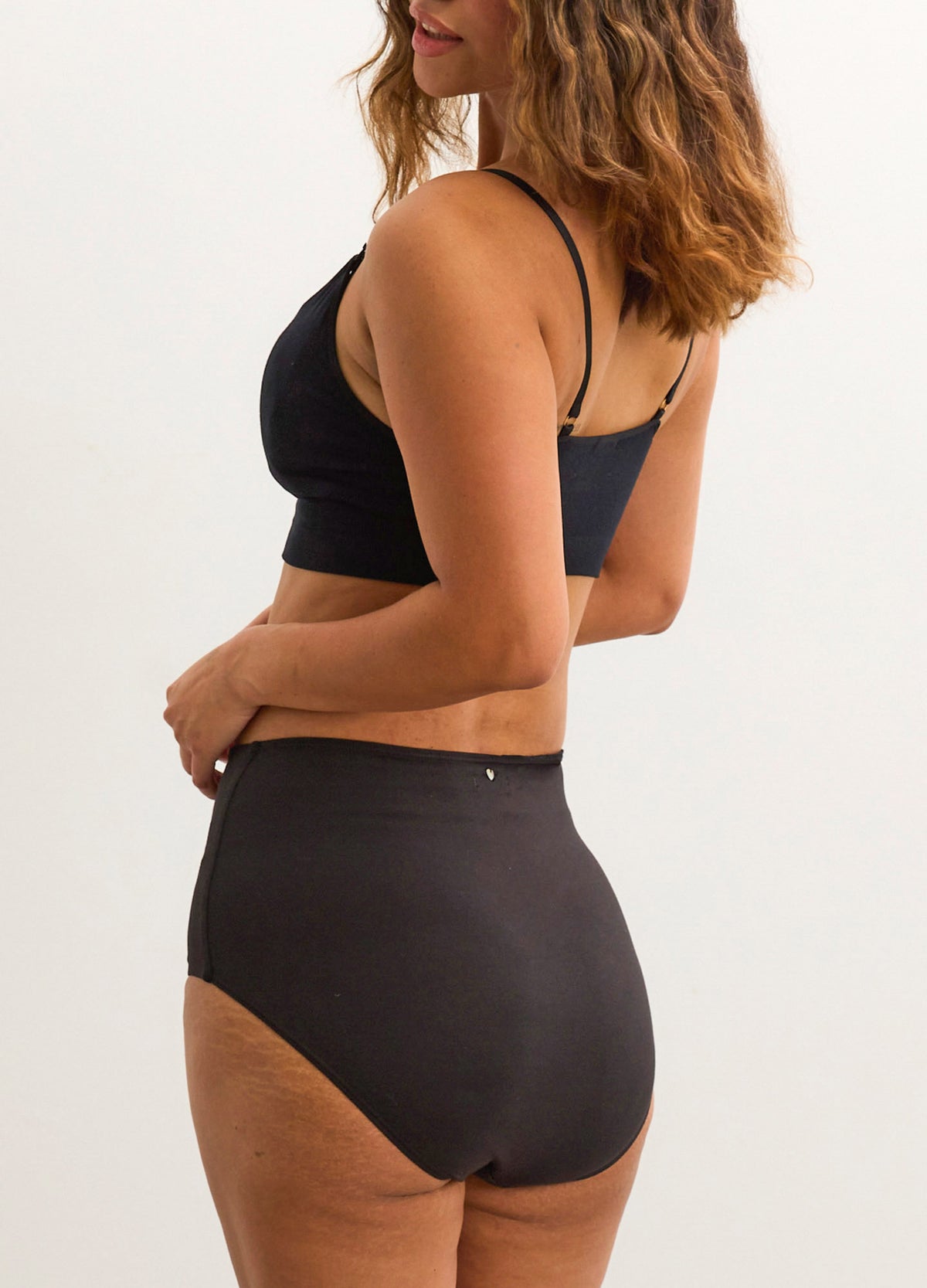Black high-waisted maternity brief with smooth fabric and full rear coverage on model.