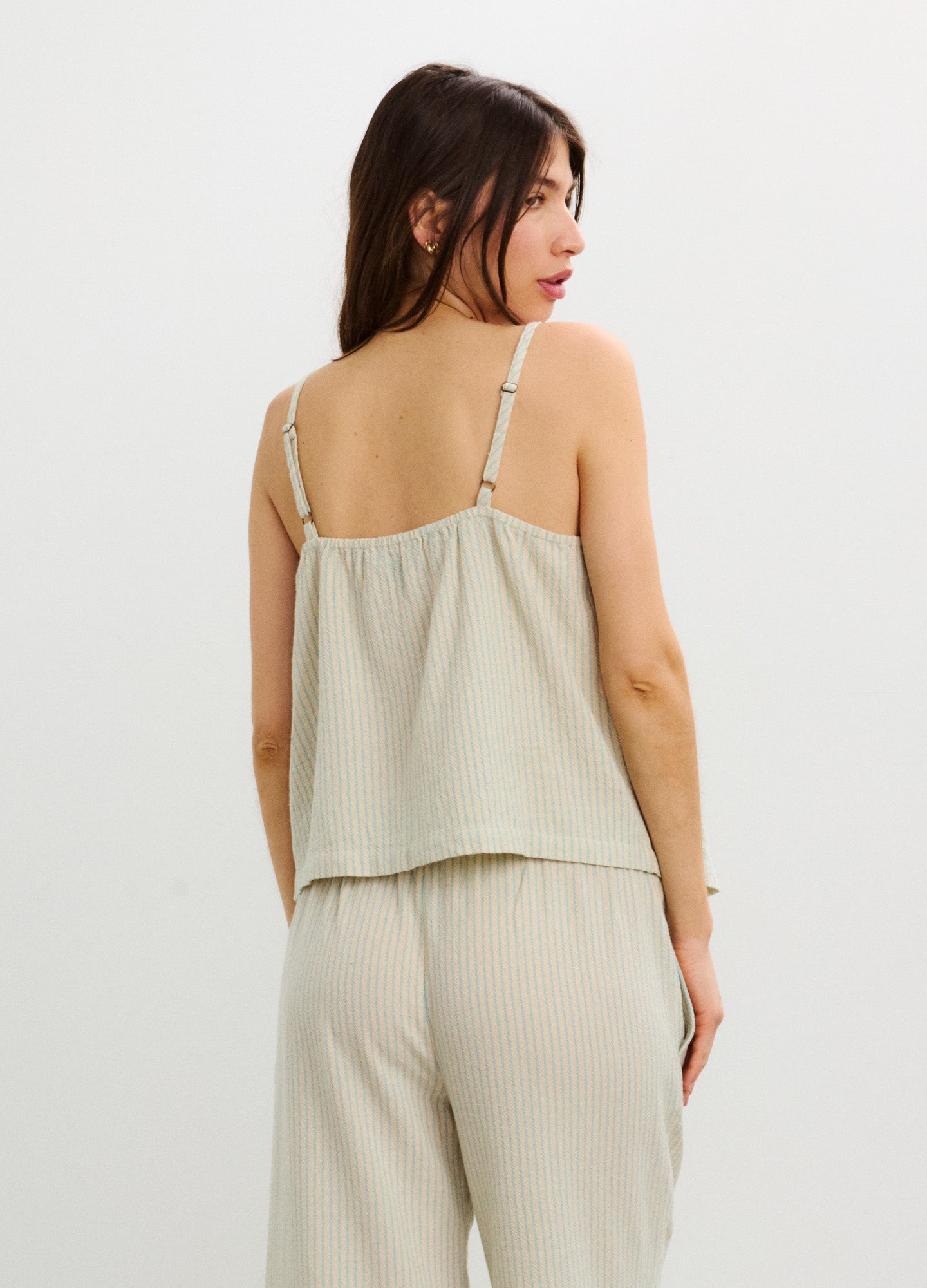 Light beige sleeveless nursing top with adjustable thin straps and loose fit, made from soft breathable fabric.