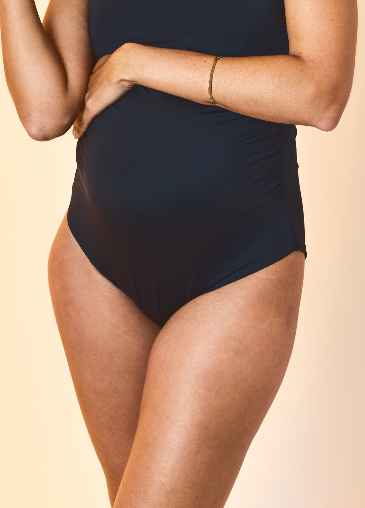 Navy blue one-piece maternity swimsuit with ruched sides designed for pregnant bodies.