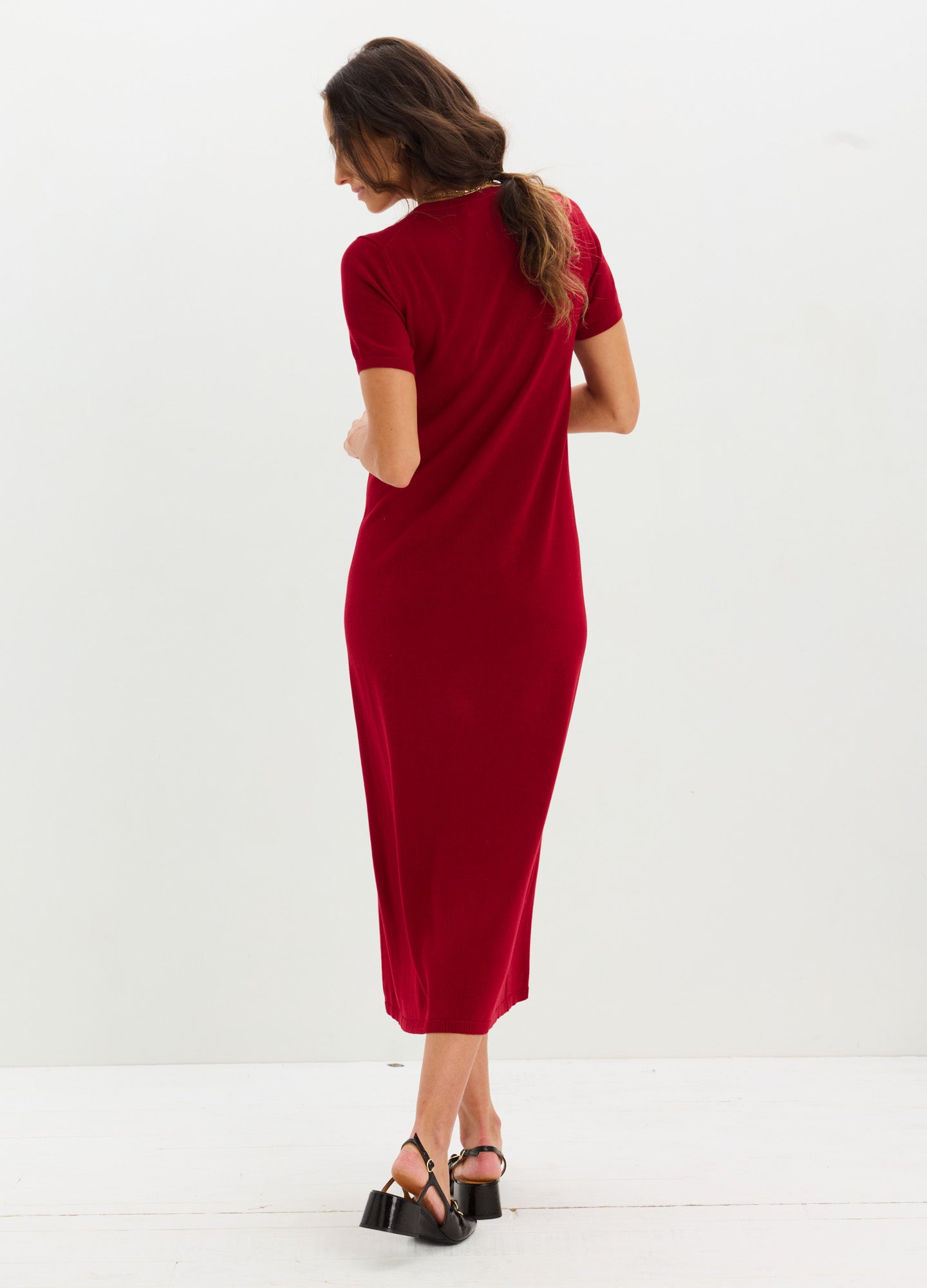 Red knit maternity dress with short sleeves and a midi length on pregnant model.