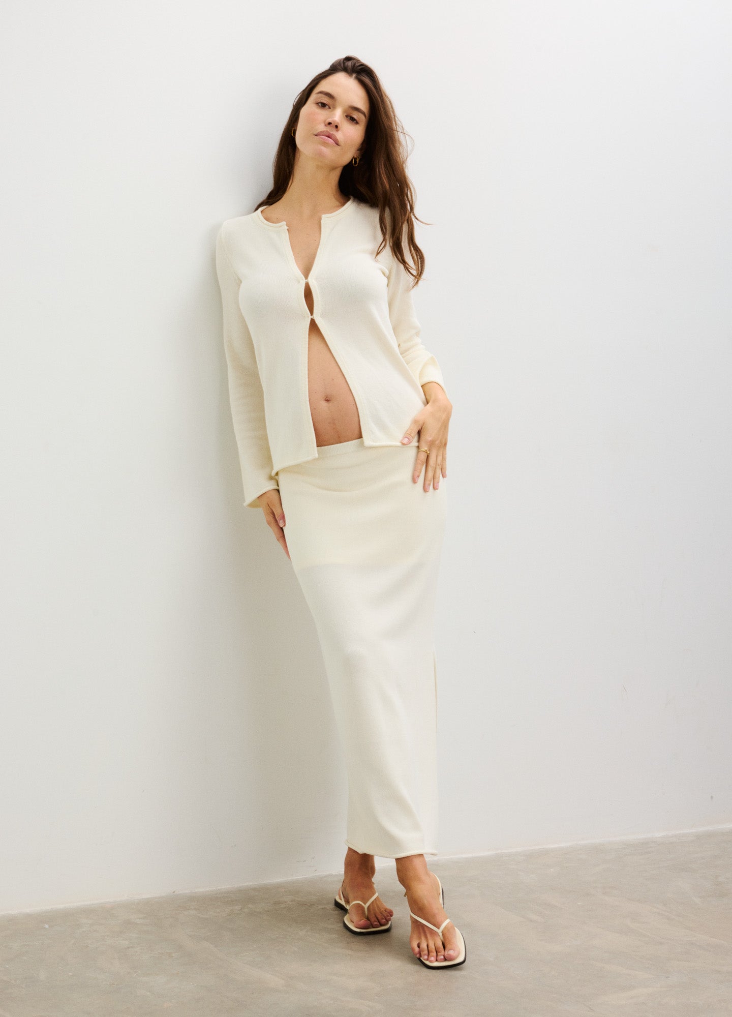 Cream-colored maternity skirt with matching cropped cardigan, lightweight knit, relaxed fit.