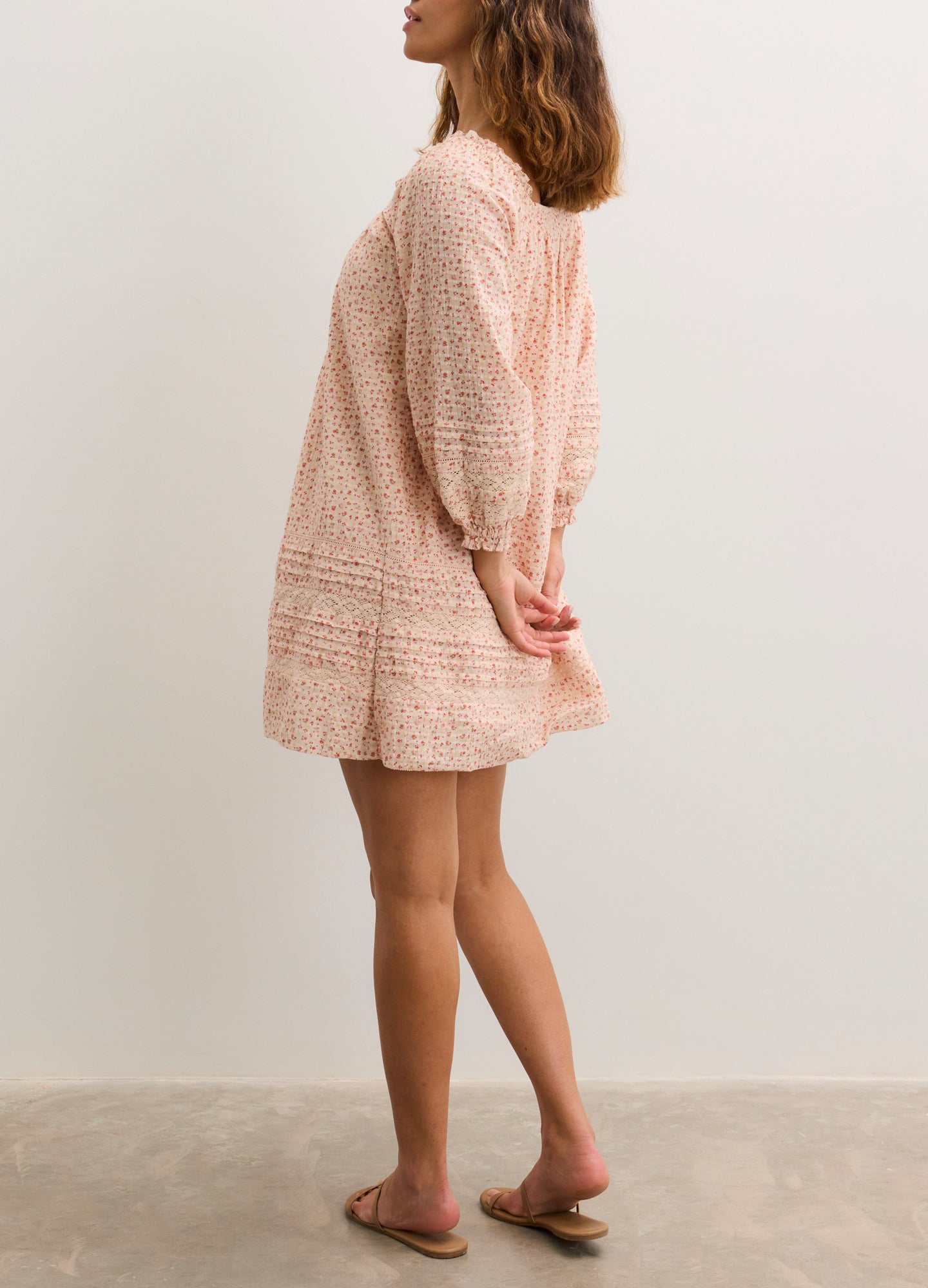 Light pink knitted maternity mini dress with long puff sleeves and tiered skirt hem.