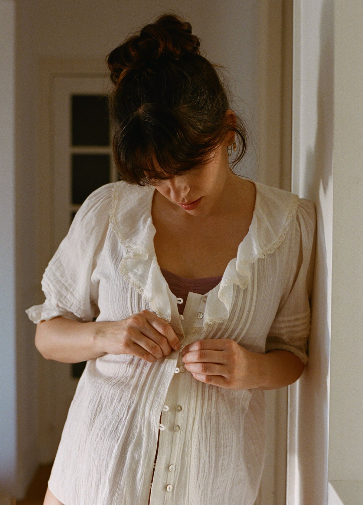 Soft white maternity nursing blouse with delicate buttons and pintuck detailing, short puff sleeves.
