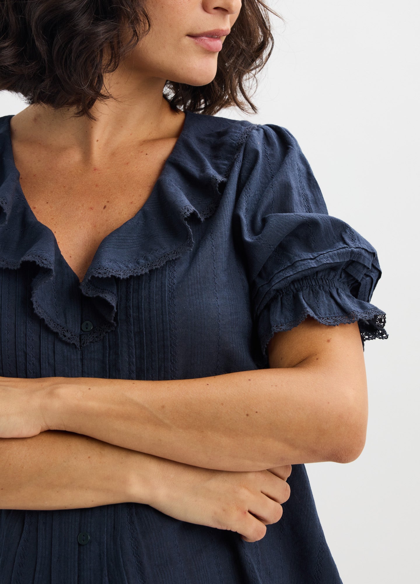 Navy blue maternity blouse with ruffled collar and puffed short sleeves, textured fabric.