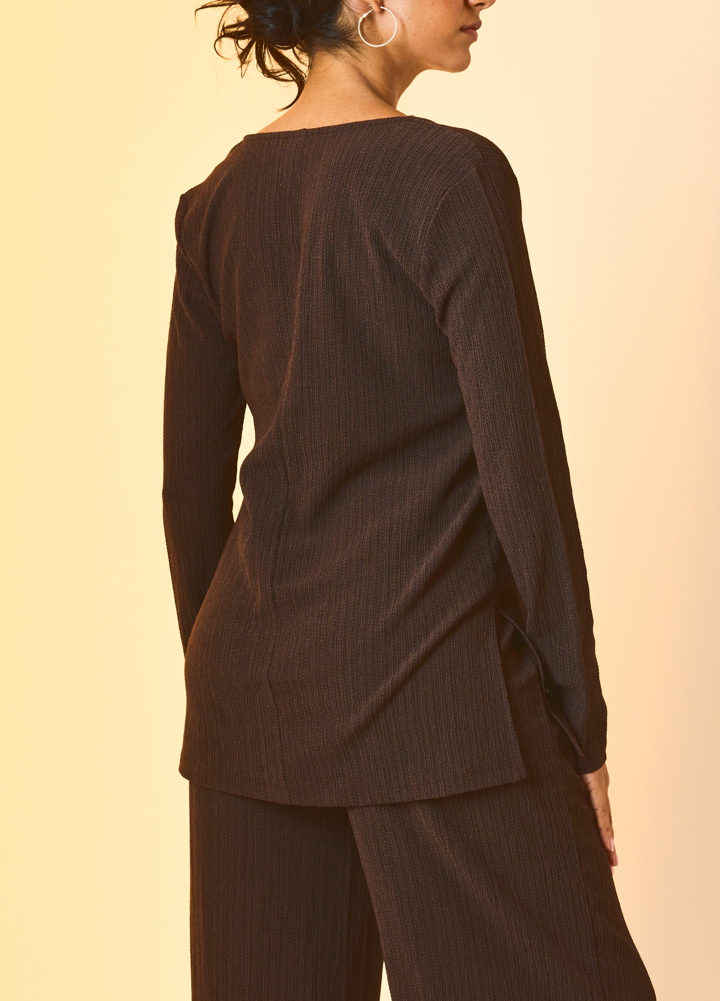 Black long-sleeve maternity shirt with ribbed texture and side slits, styled for pregnancy.