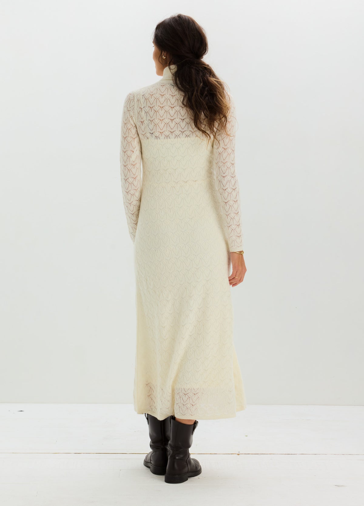 Ivory pointelle knit dress with a fitted bodice, long sheer-patterned sleeves, and flowing ankle-length skirt.