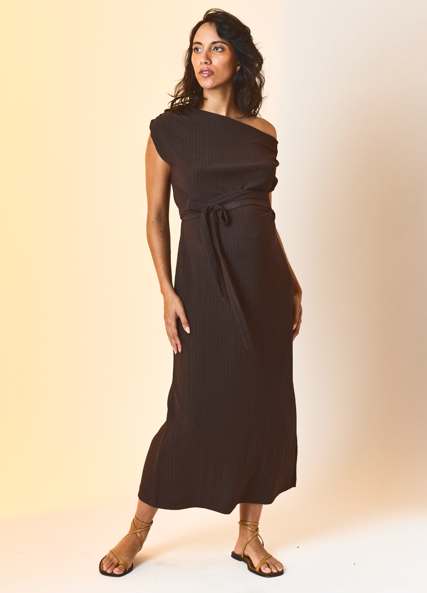 Black sleeveless midi maternity dress with one-shoulder design and waist tie, worn by pregnant model.