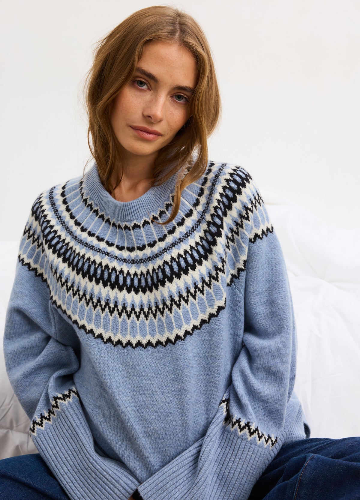 Light blue fair isle pullover with white, black, and beige patterns, ribbed cuffs and hem, relaxed fit for maternity wear.