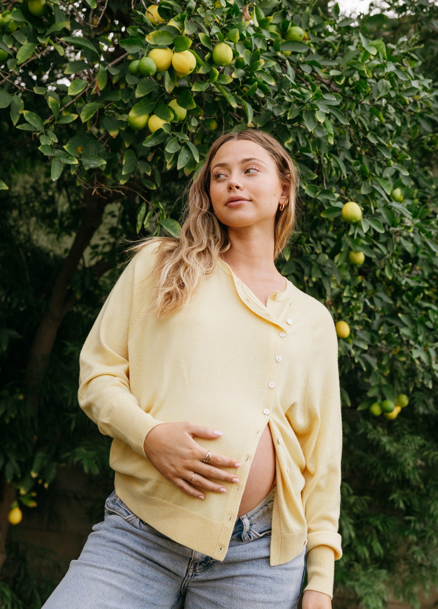 Soft yellow maternity cardigan with buttons, relaxed fit, lightweight knit, worn open over baby bump.