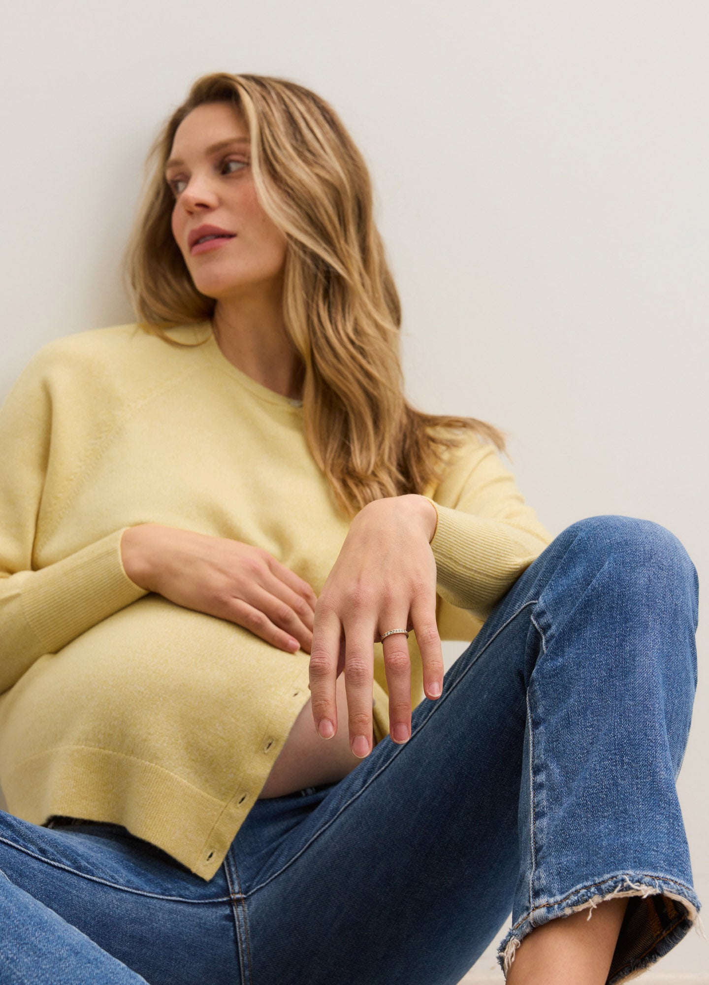 Soft yellow maternity cardigan with long sleeves and a relaxed fit, styled with blue jeans.