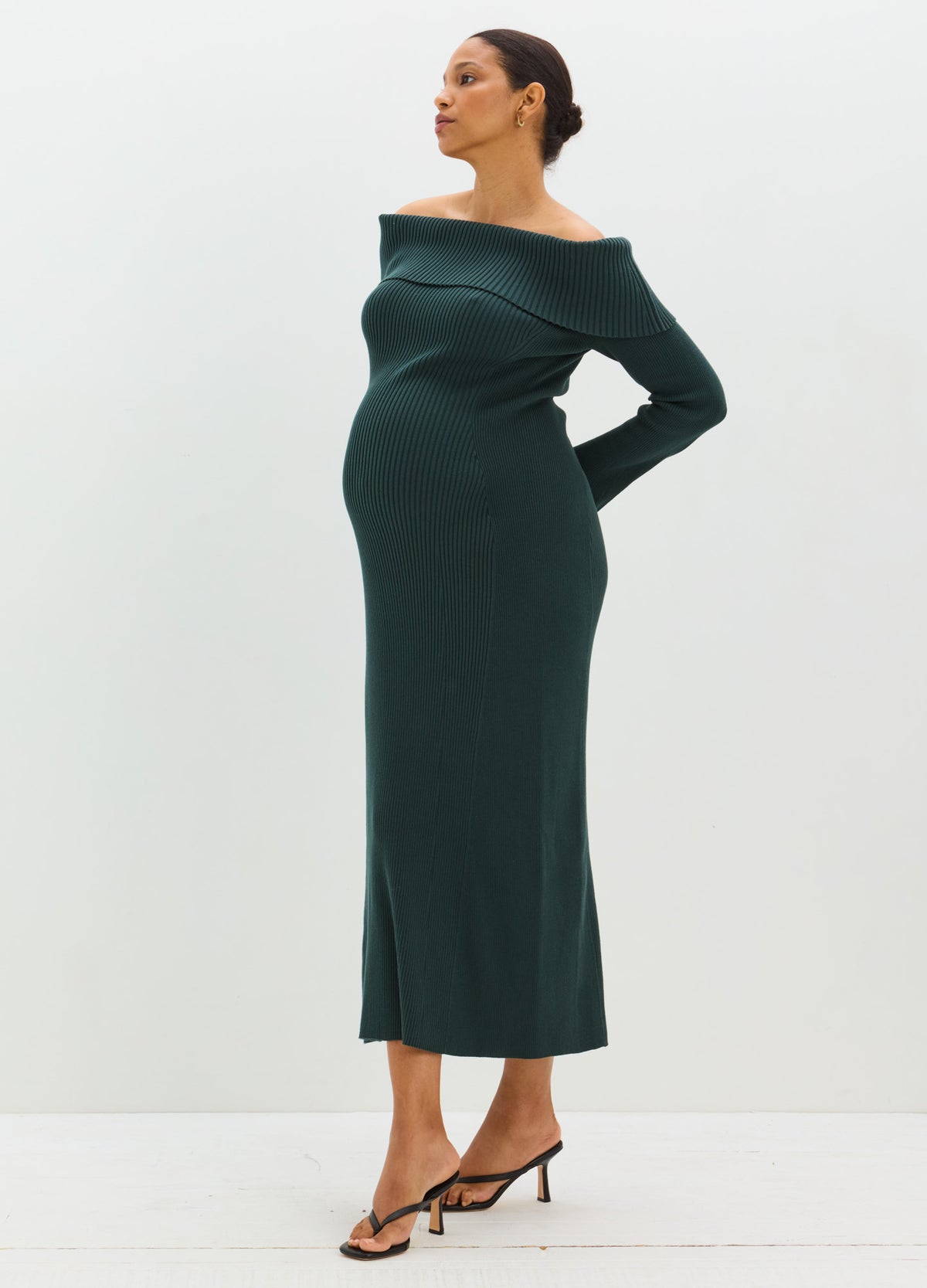 Dark green off-the-shoulder sweater dress with a fitted maternity silhouette and long sleeves.