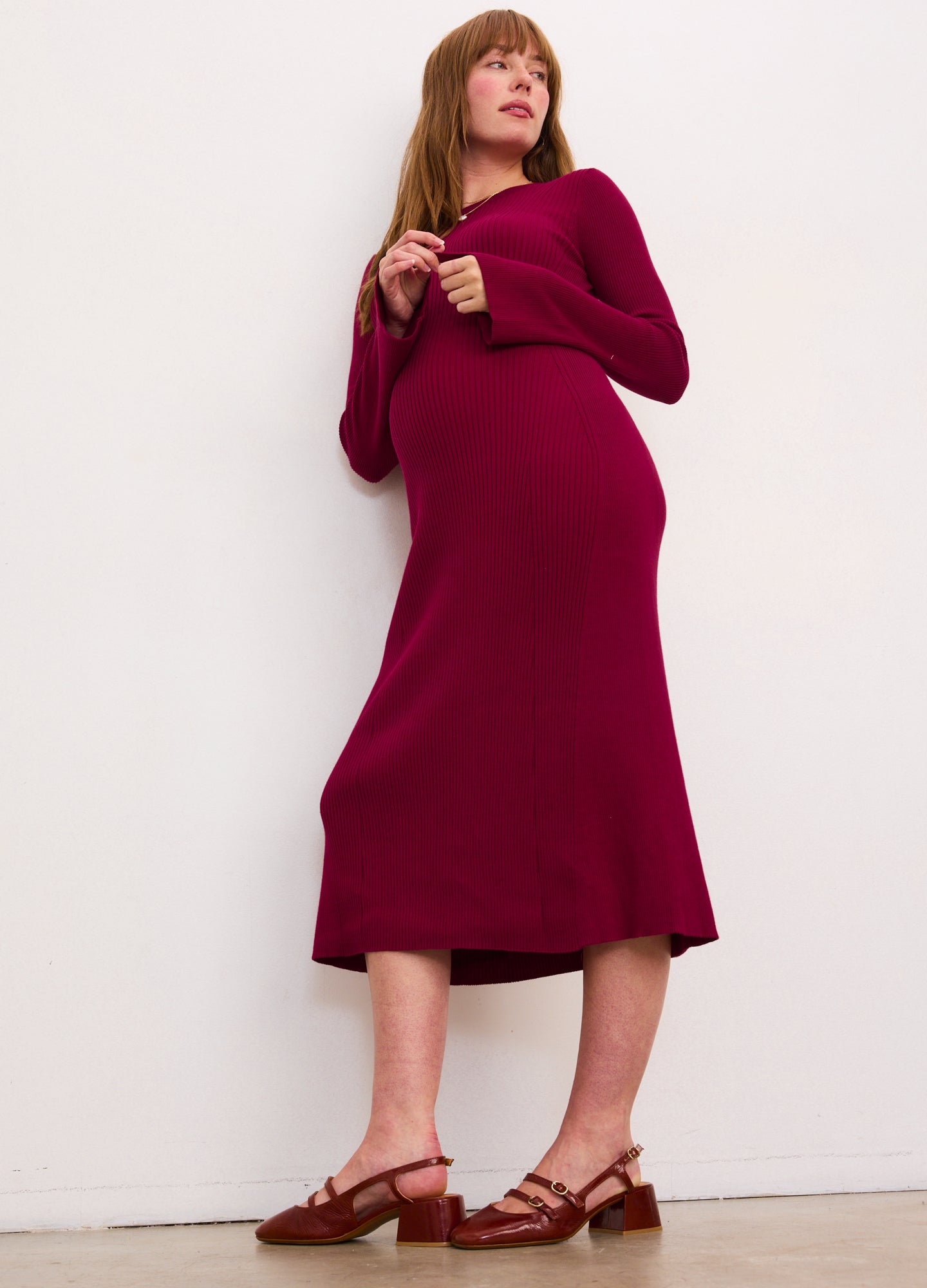 Burgundy ribbed midi dress with long sleeves and a high neckline, designed to gently fit a pregnant silhouette.