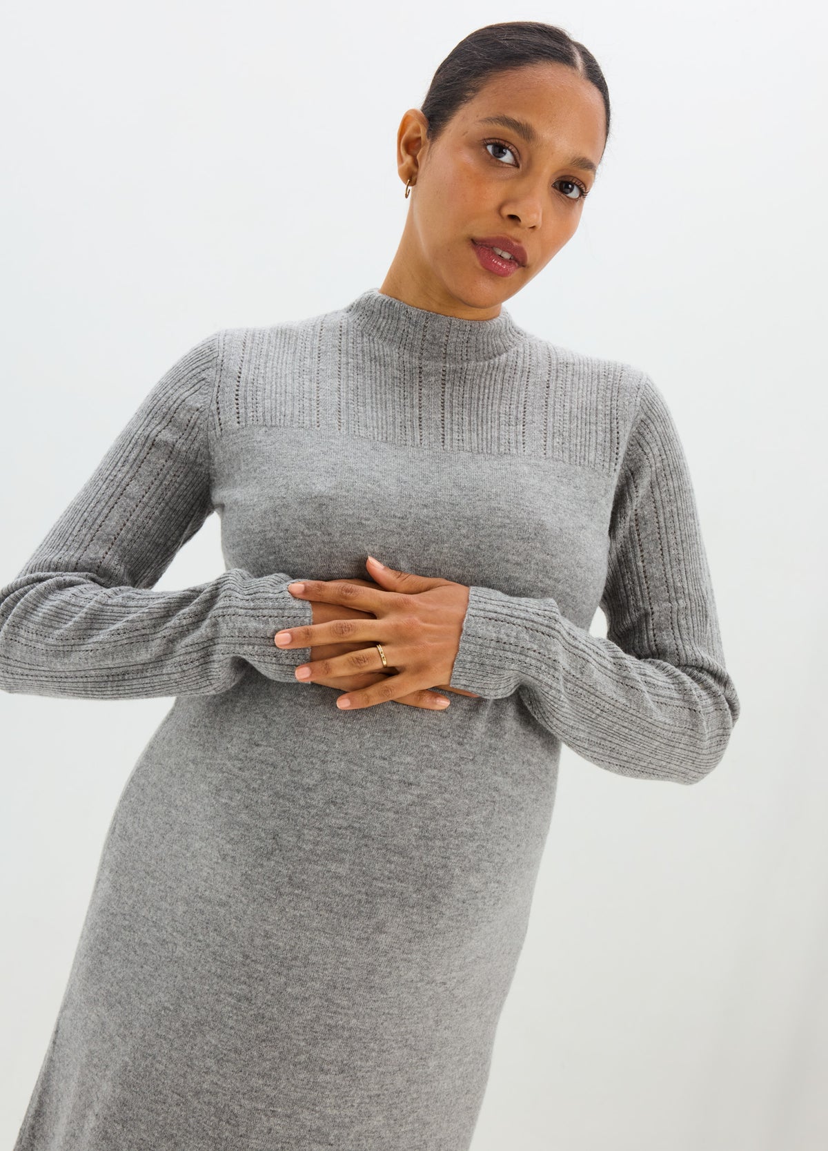 Gray ribbed pointelle maternity sweater dress with a high neck, long sleeves, and a fitted shape that highlights the.