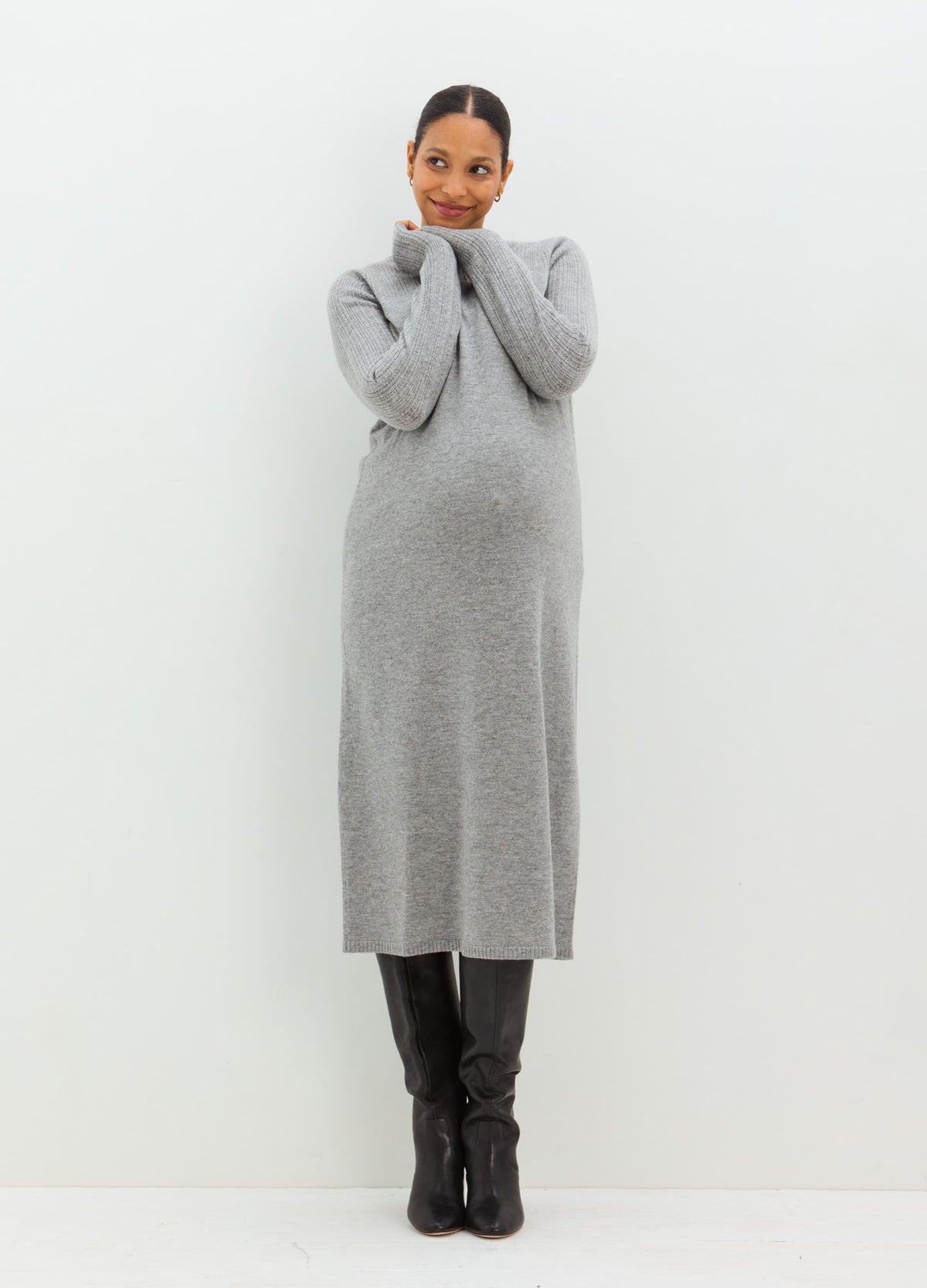 Pregnant model wearing a long gray pointelle knit dress with a fitted silhouette and high neckline.