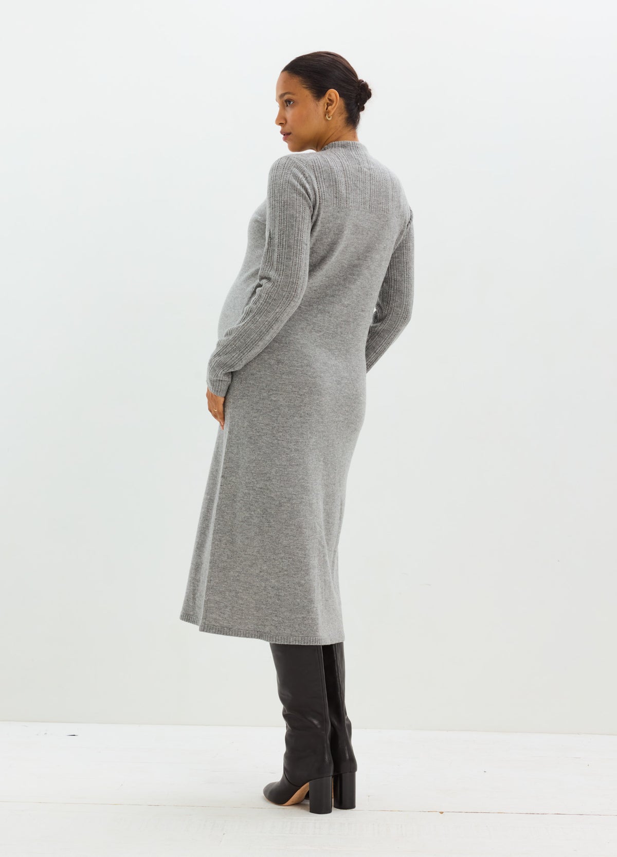 Pregnant model wearing a long gray pointelle knit maternity dress with a fitted silhouette and long sleeves.