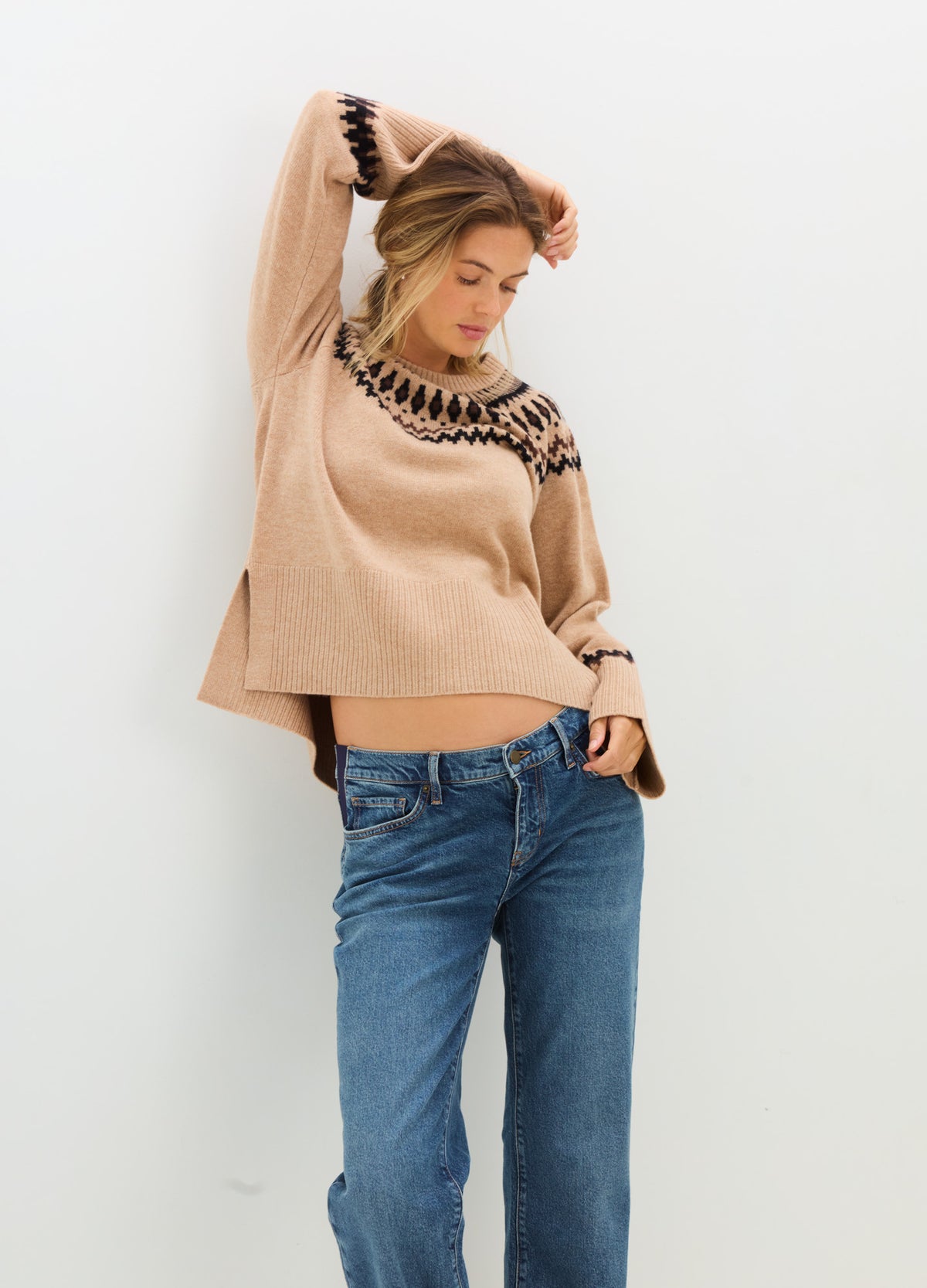 Blush pink maternity sweater with black Fair Isle trim at the neckline and cuffs, worn with blue jeans.