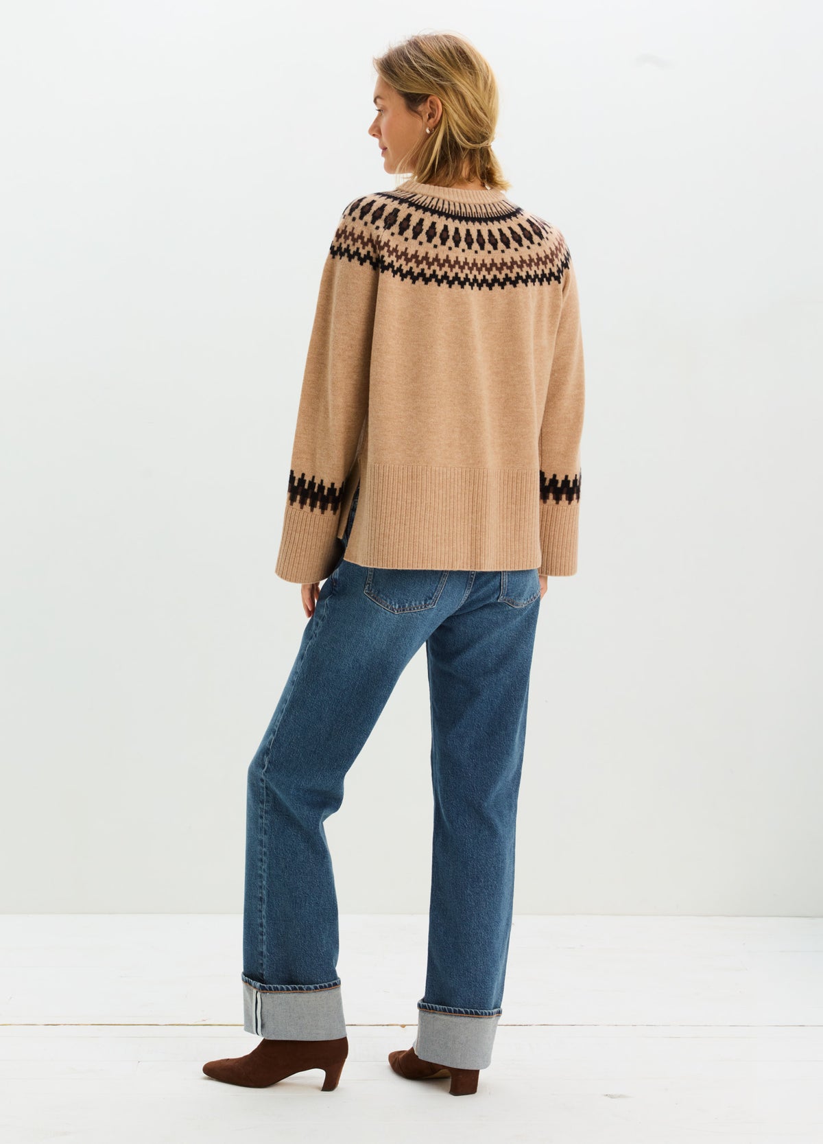 Relaxed tan Fair Isle maternity sweater with black geometric bands, shown with blue jeans and cuffed hems.