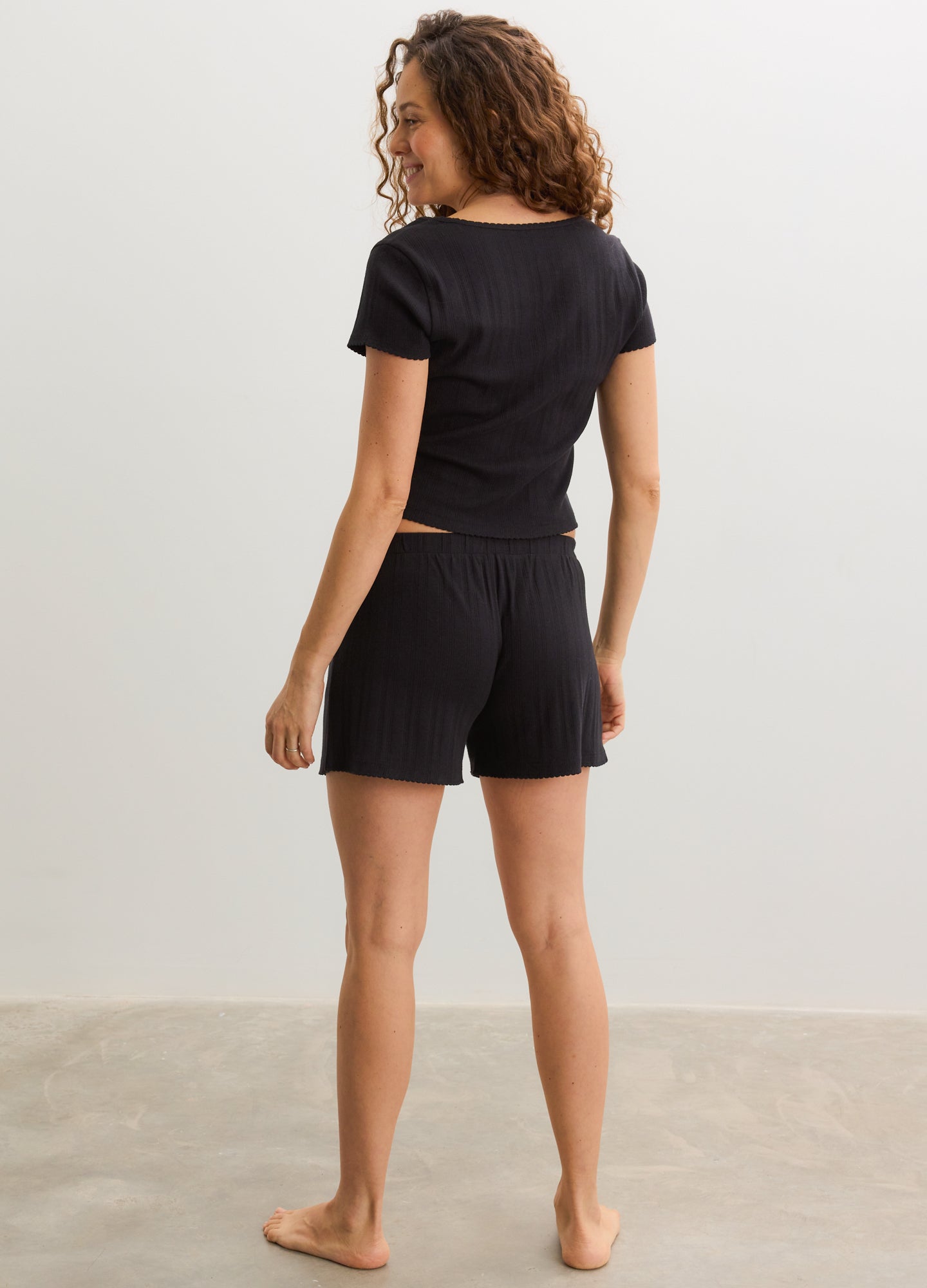 Black short-sleeve maternity tee with subtle pointelle knit, paired with matching black maternity shorts.