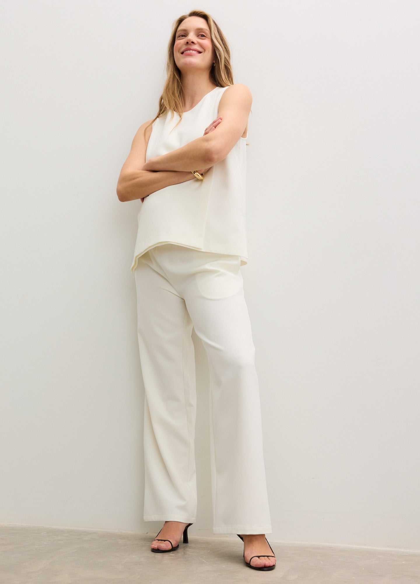 Ivory wide-leg maternity pants with a soft elastic waistband, paired with a sleeveless ivory top and black open-toe heels.