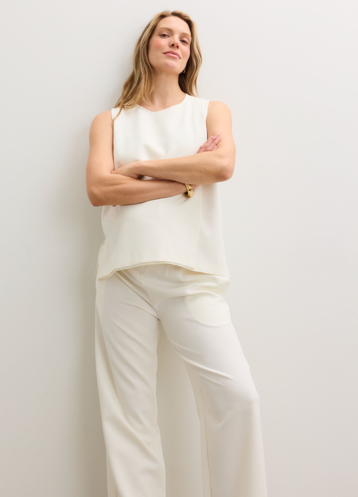 Cream maternity pants with a relaxed fit and a soft, stretchy waistband paired with a sleeveless cream top.
