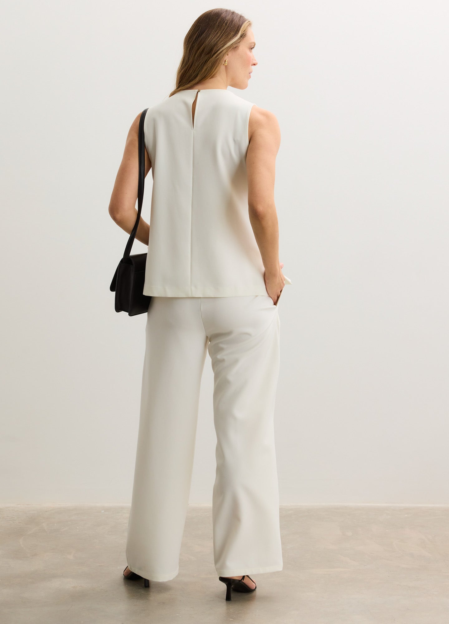 White sleeveless maternity top with relaxed fit paired with high-waisted wide-leg maternity pants.