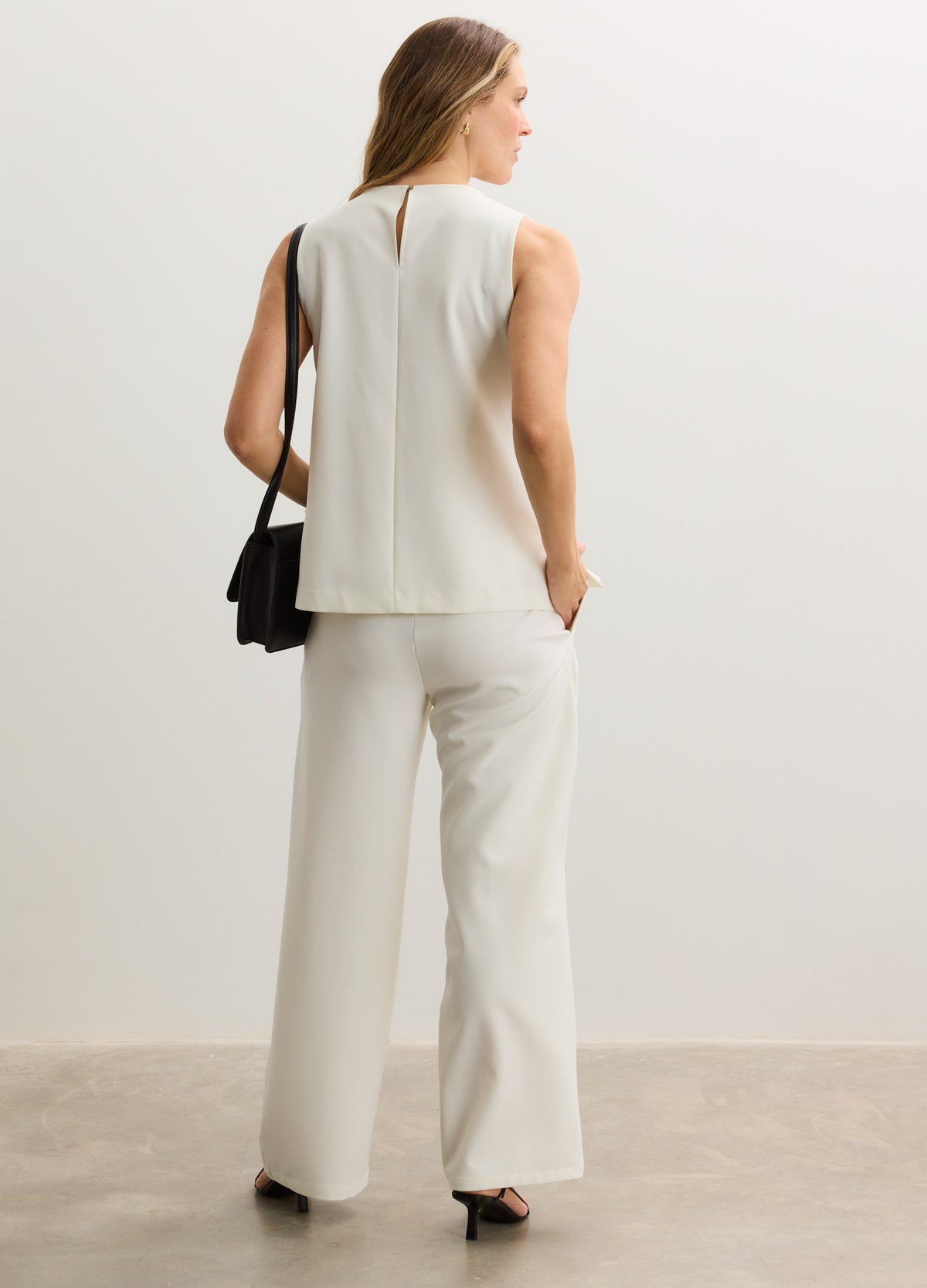 White sleeveless maternity top with relaxed fit paired with high-waisted wide-leg maternity pants.