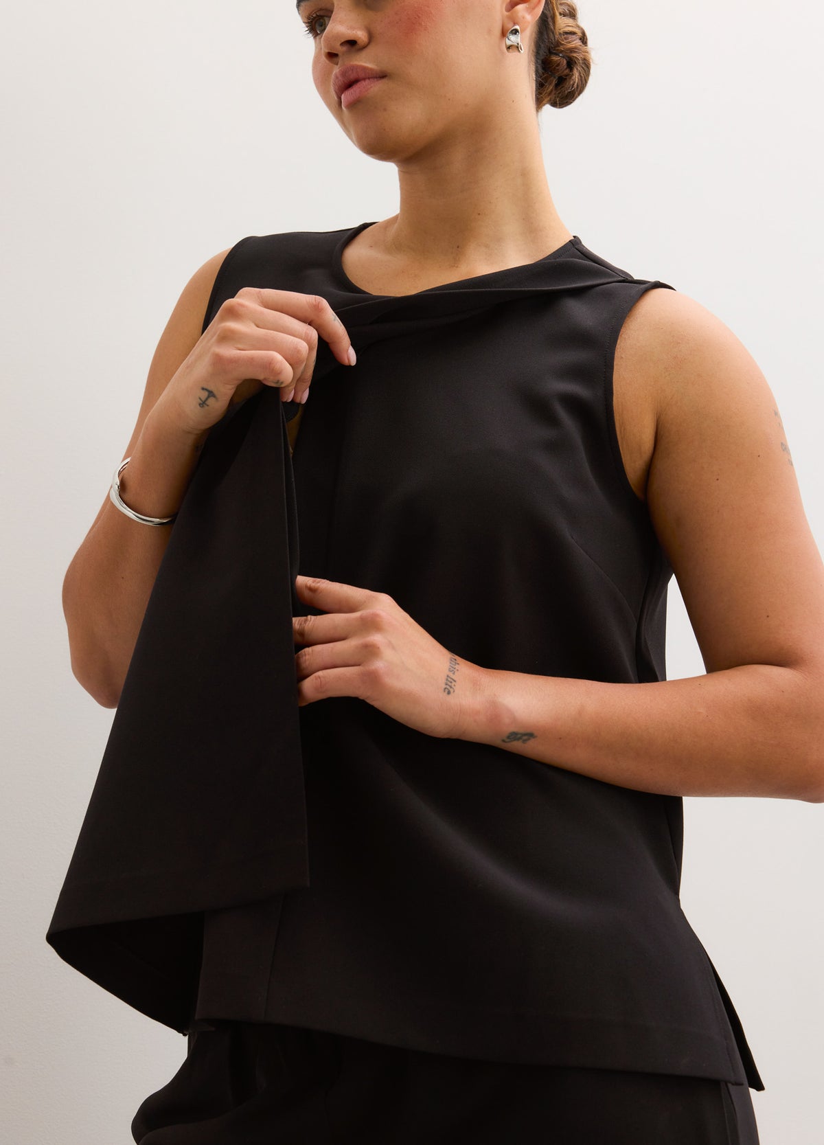 Black sleeveless nursing tank with layered front flap detail, soft stretchy fabric, designed for maternity and breastfeeding.