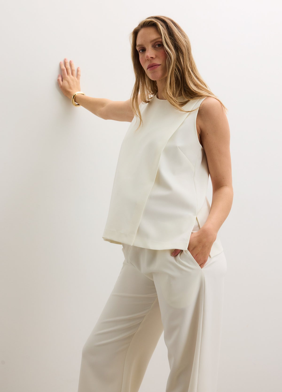 Cream-colored sleeveless nursing tank with a relaxed fit, soft fabric, and subtle side slits, styled for maternity.