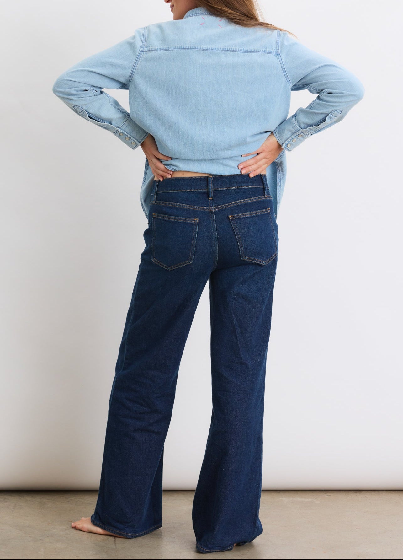 Dark blue denim wide-leg maternity jeans with high stretch waistband, worn by pregnant woman.