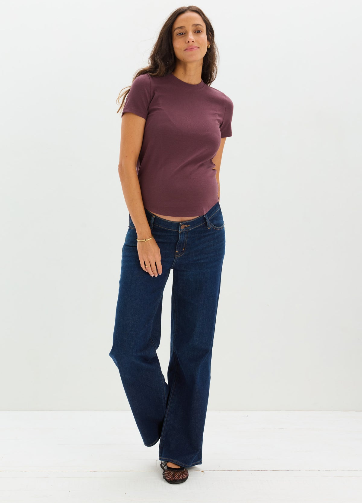 Dark blue wide-leg maternity jeans with a stretchy waistband worn by pregnant woman in a purple t-shirt.