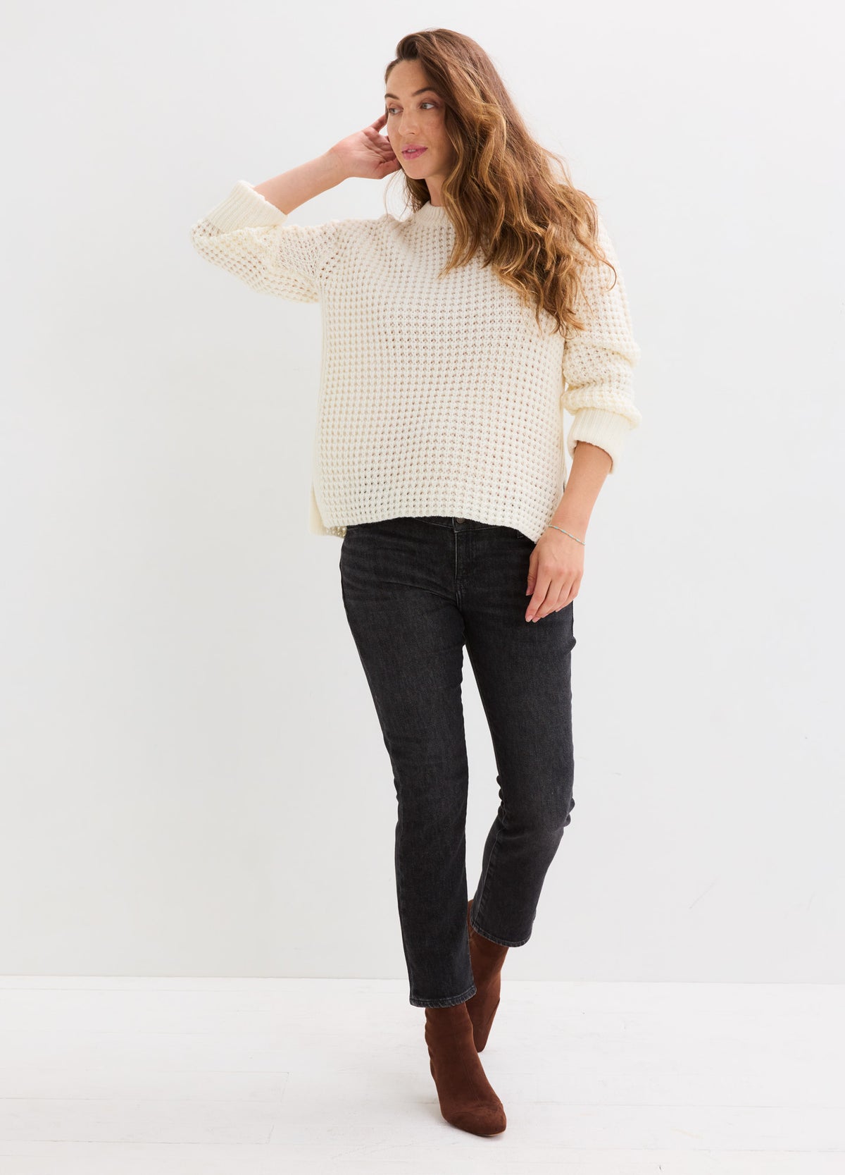Cream waffle-knit sweater with a relaxed fit, dropped shoulders, and three-quarter sleeves, styled with black jeans.