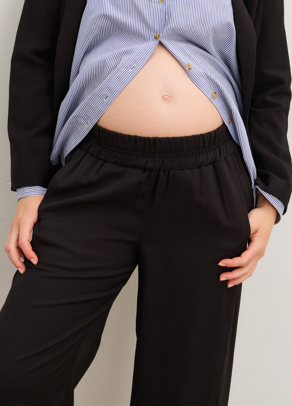 The Soft Tailored Pull On Trouser - Black soft tailored maternity trousers with a pull-on waistband, styled with a blue nursing-friendly blouse and black blazer.