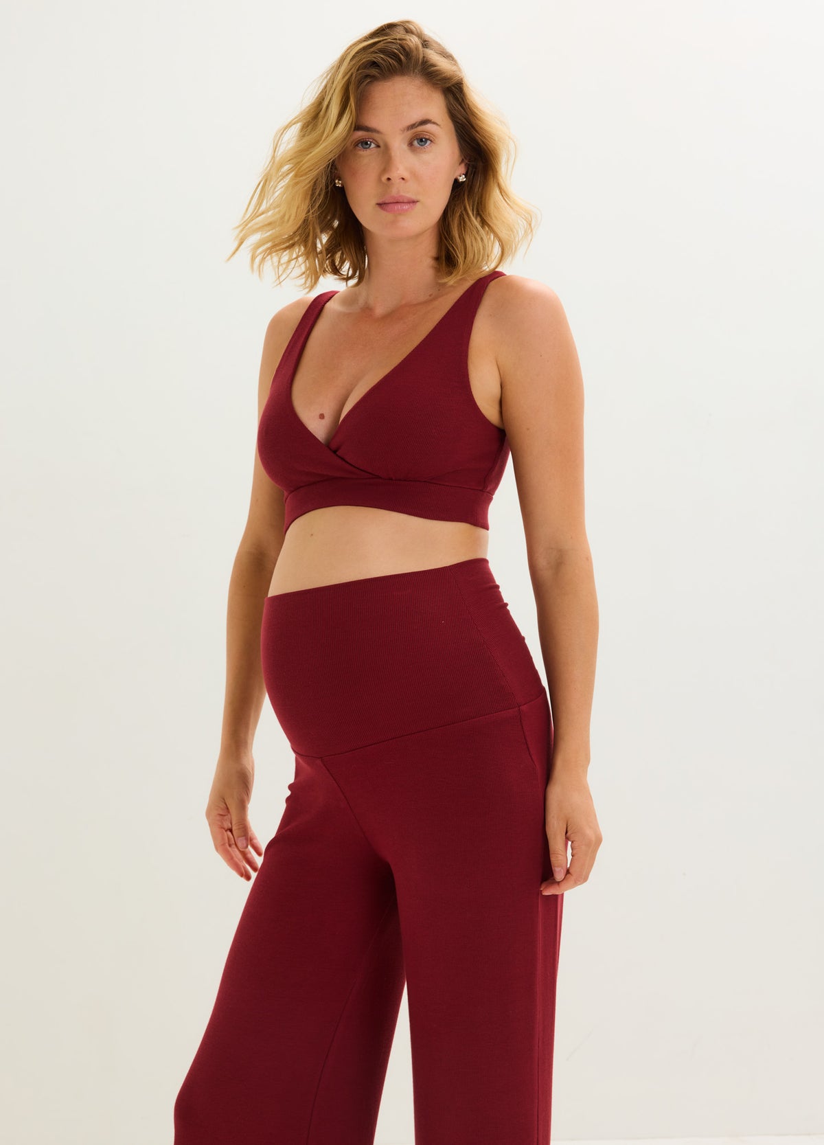 Woman wearing a cranberry ribbed maternity nursing bra with matching high-waisted pants, suited for pregnancy and every.