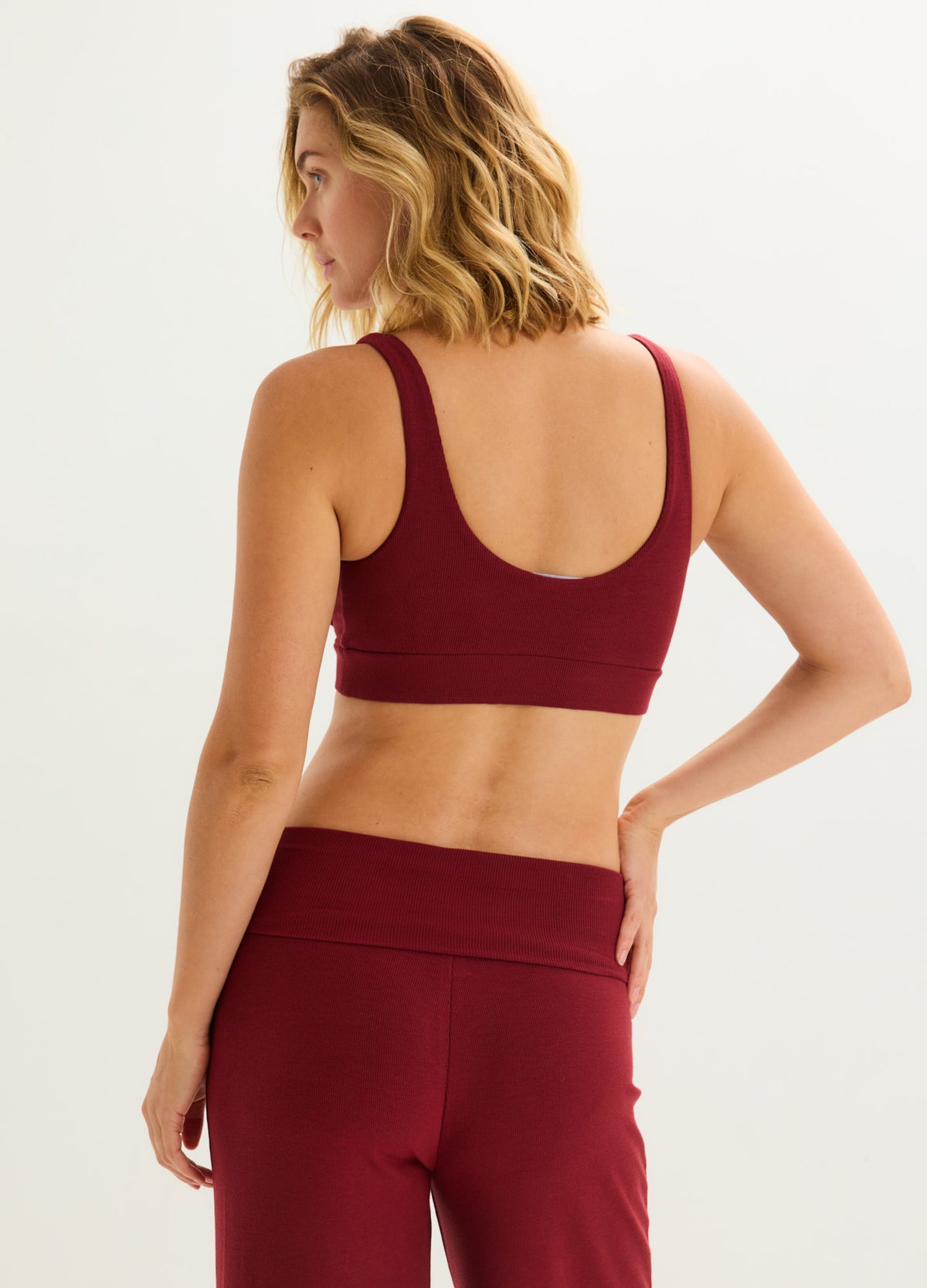 Cranberry ribbed maternity nursing bra and high-waisted leggings, shown from behind on a pregnant model.