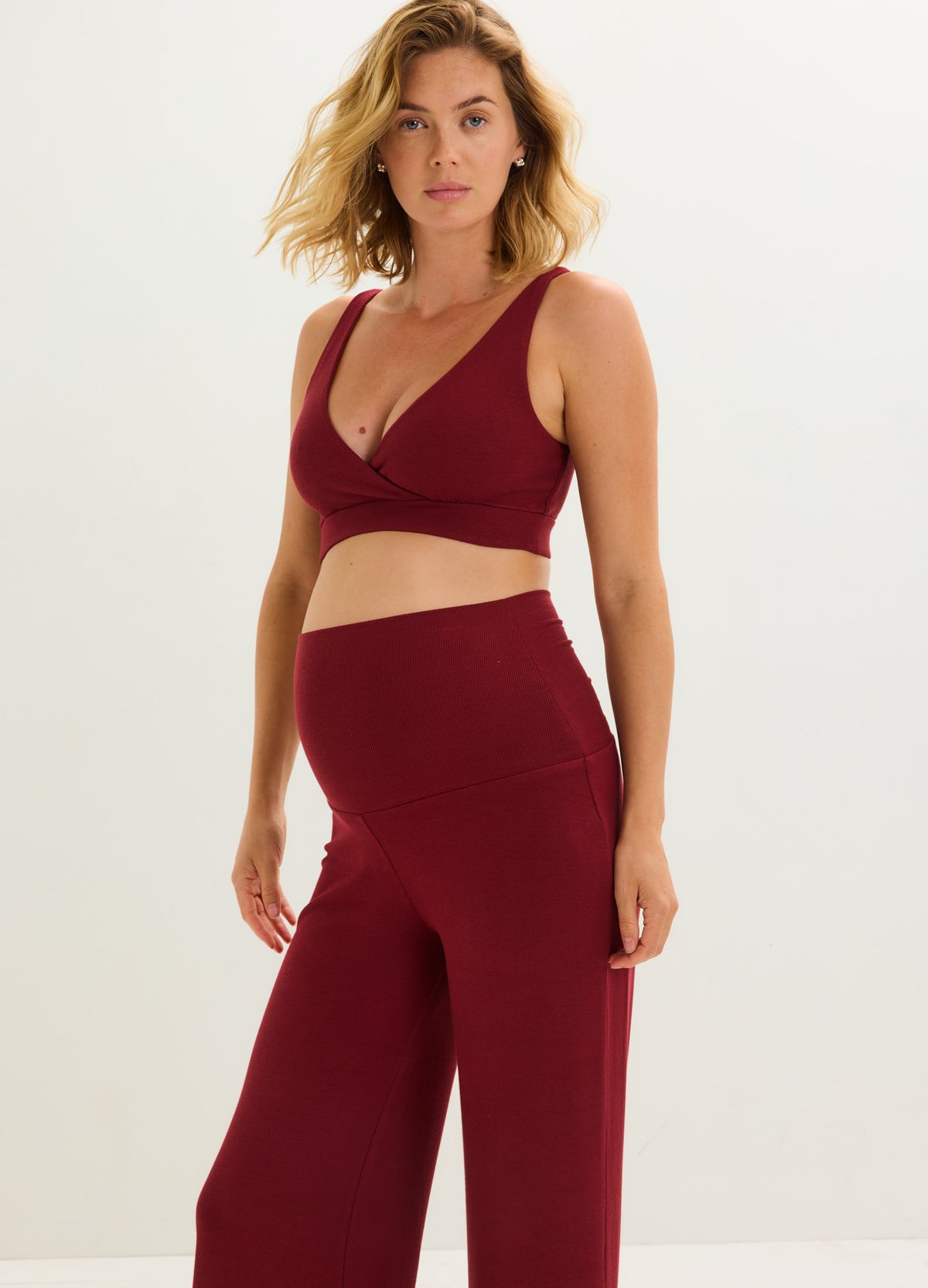 Burgundy rib-knit maternity pants with relaxed fit and high waistband designed for pregnancy comfort.