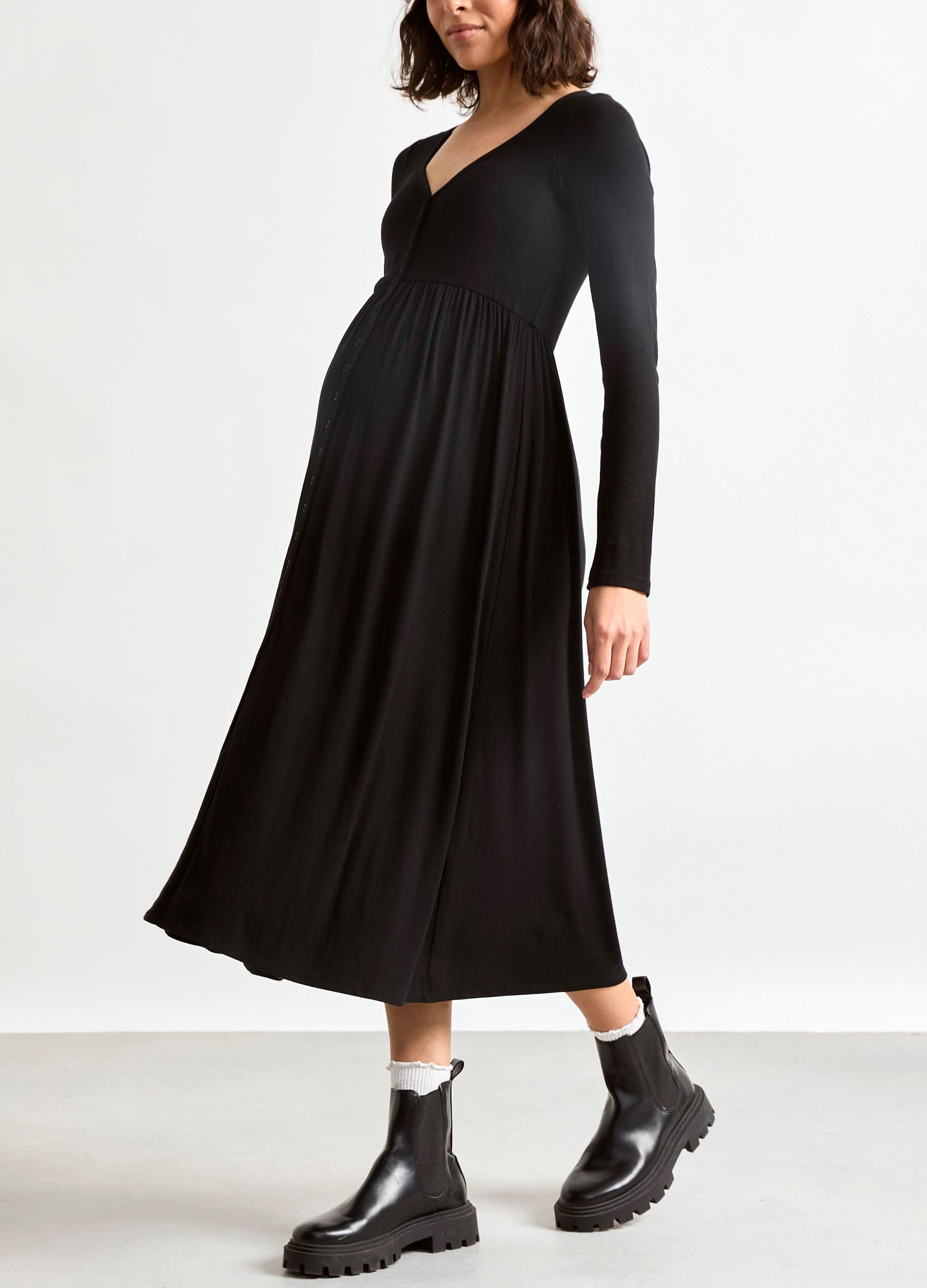 Black long-sleeve ribbed maternity dress with V-neck and flowing skirt, styled for pregnant women.