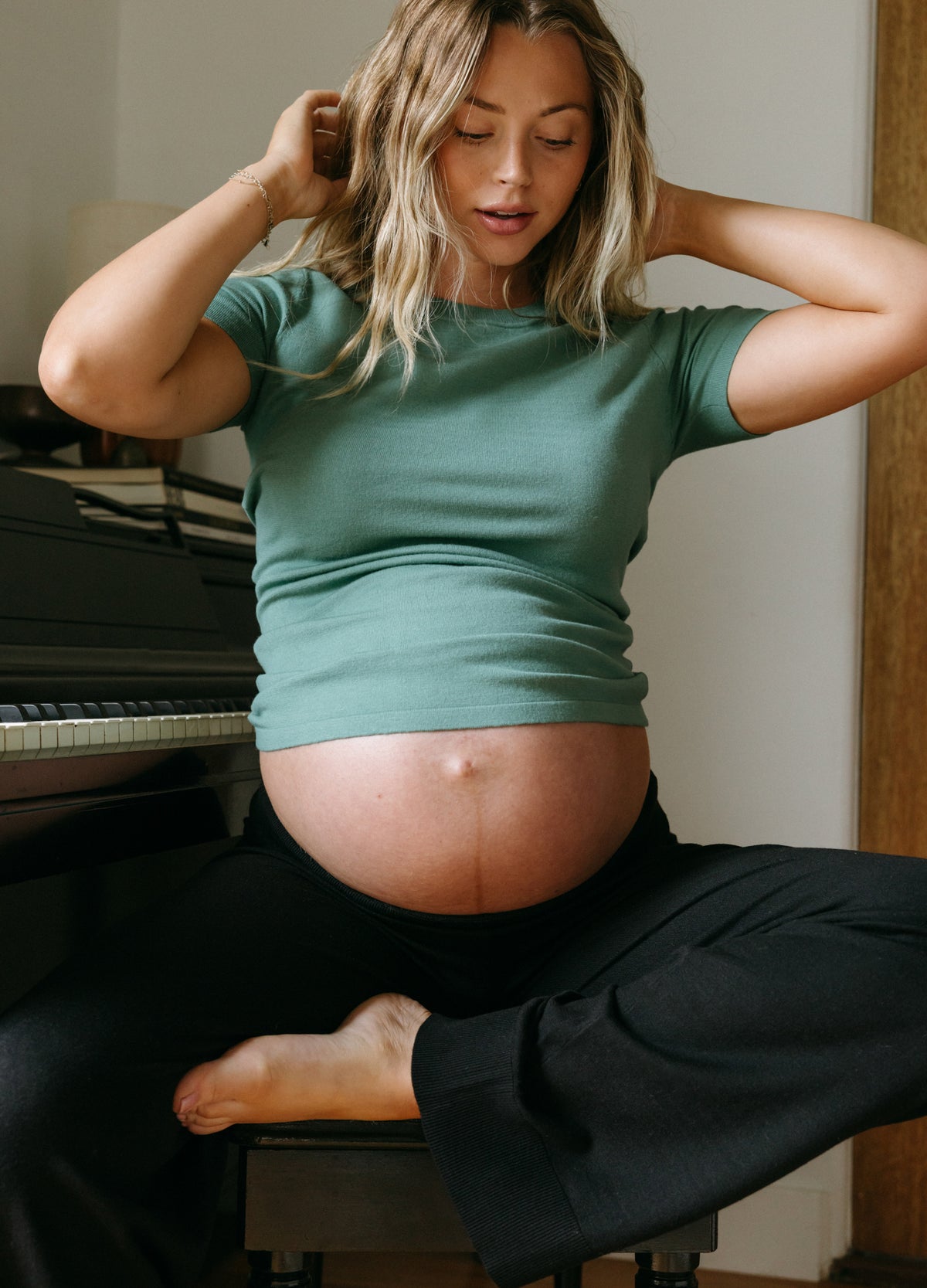 Green short-sleeve maternity knit tee with a soft, stretchy fit draping over a pregnant belly.