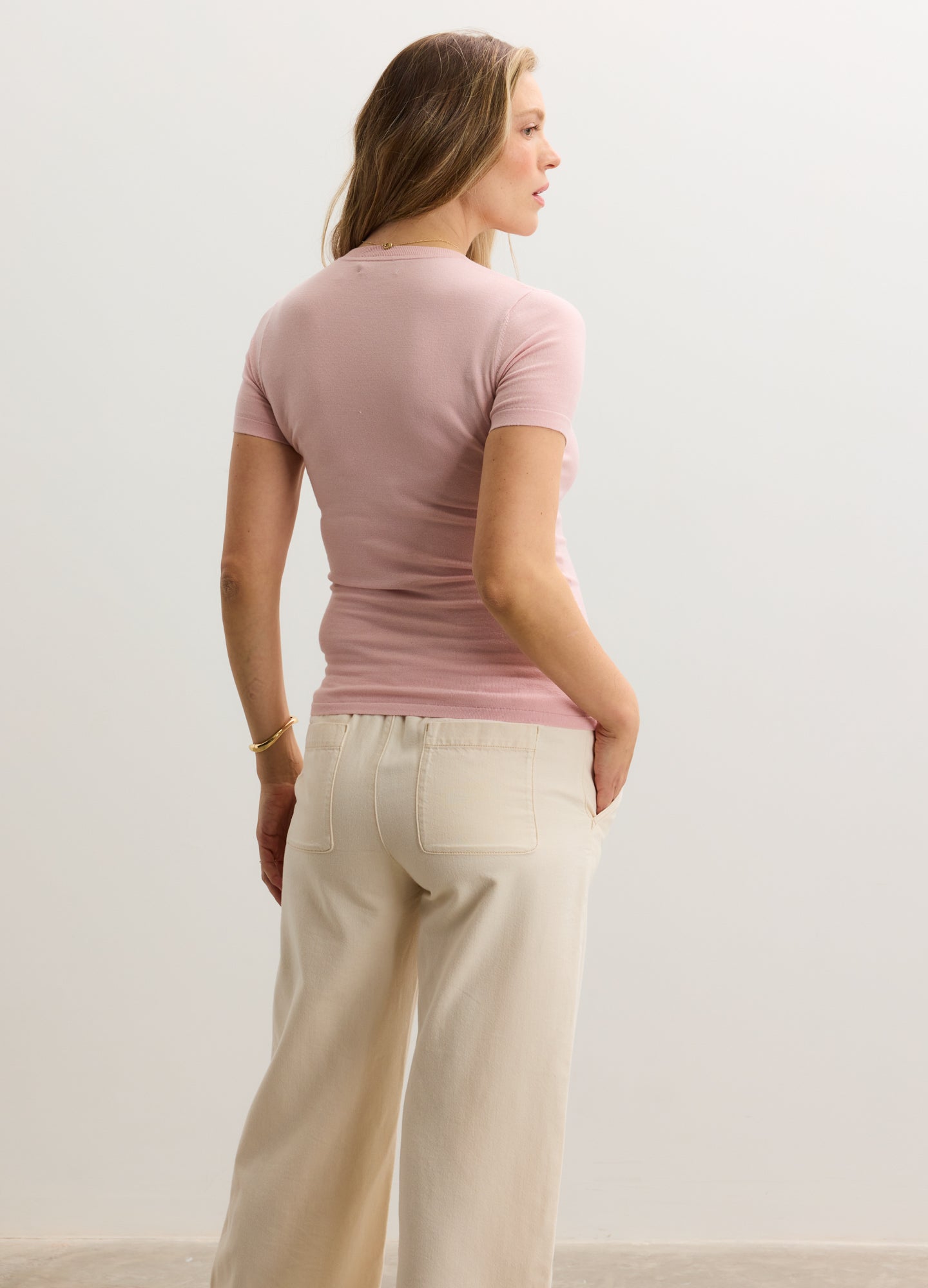 Mauve short-sleeve knit tee with fitted silhouette, worn by pregnant model, paired with cream wide-leg pants.