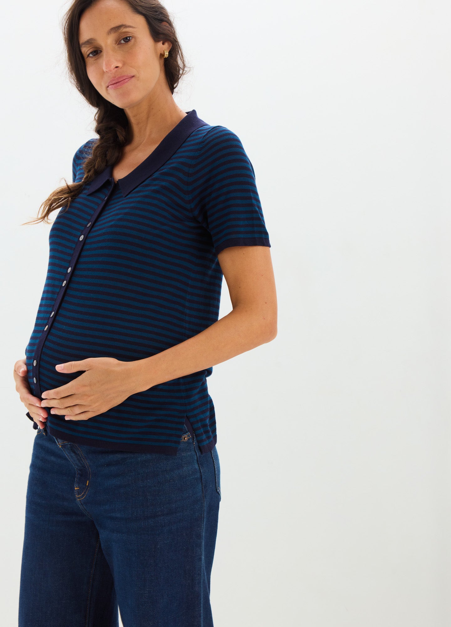 Navy blue and black striped short-sleeve maternity shirt with button front, fitted over pregnant belly.