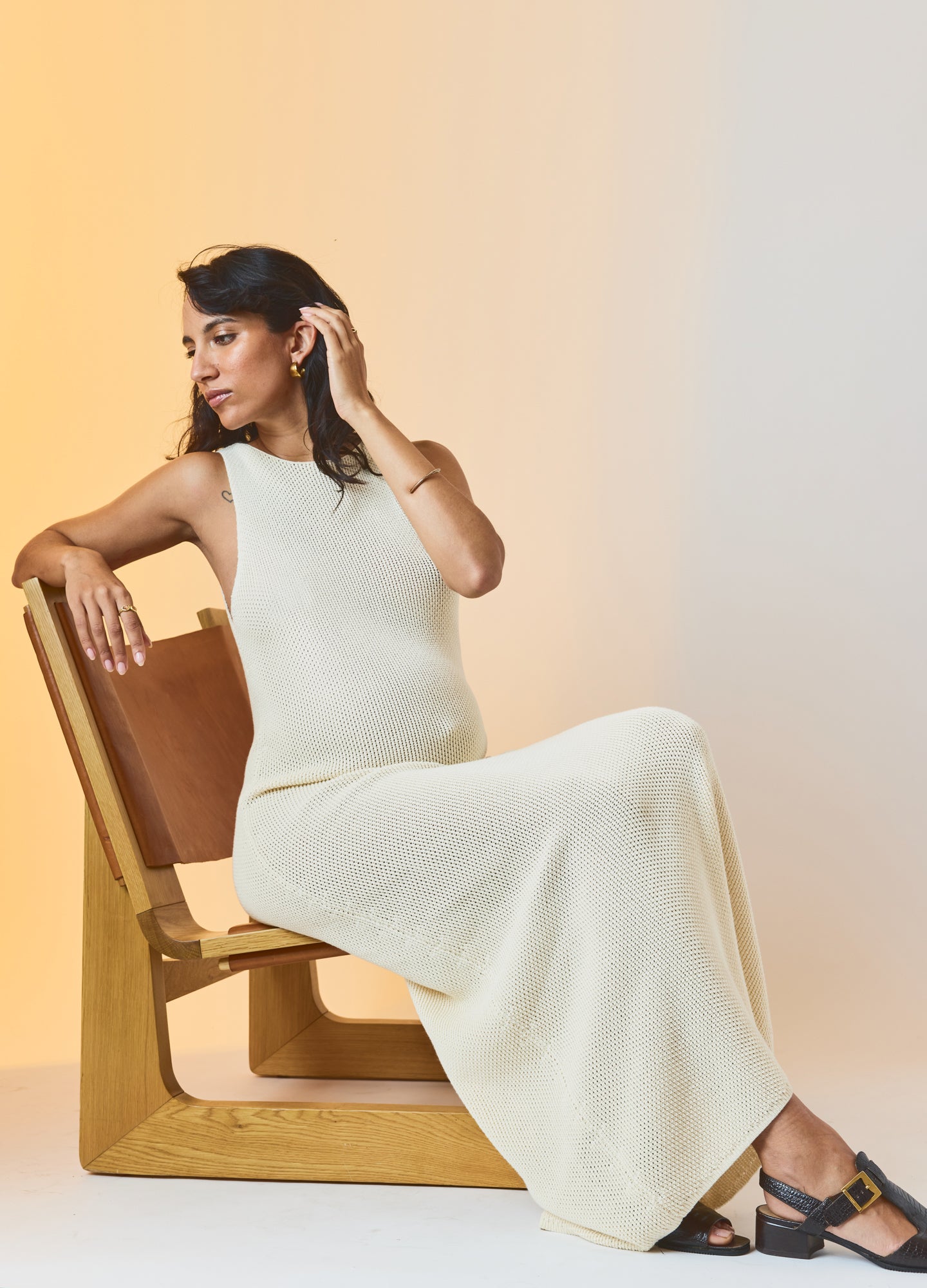 Cream-colored sleeveless maternity maxi dress with fitted bodice and flowing skirt.