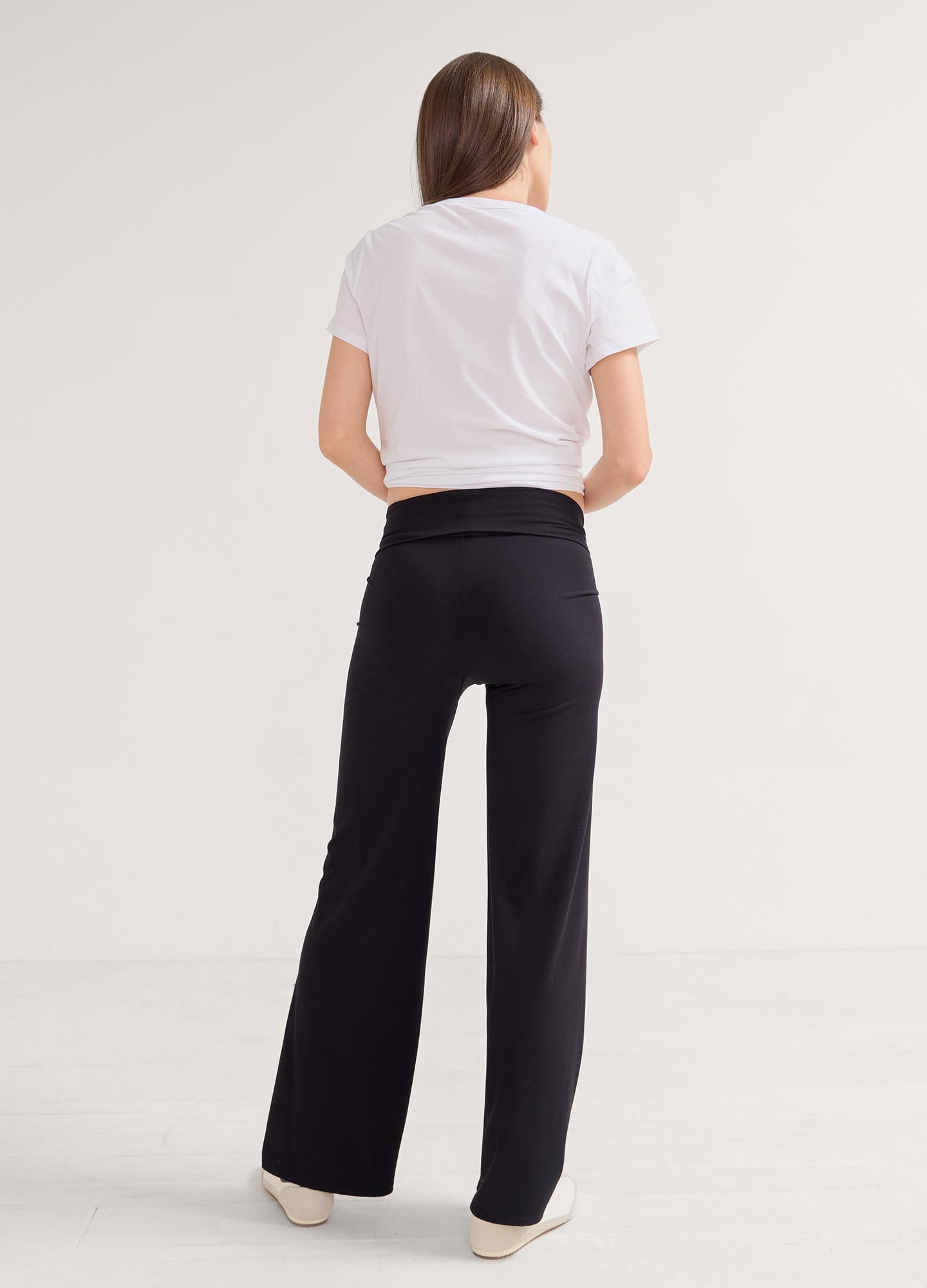 Black high-waist maternity pants with wide legs and stretch fabric, modeled from the back.