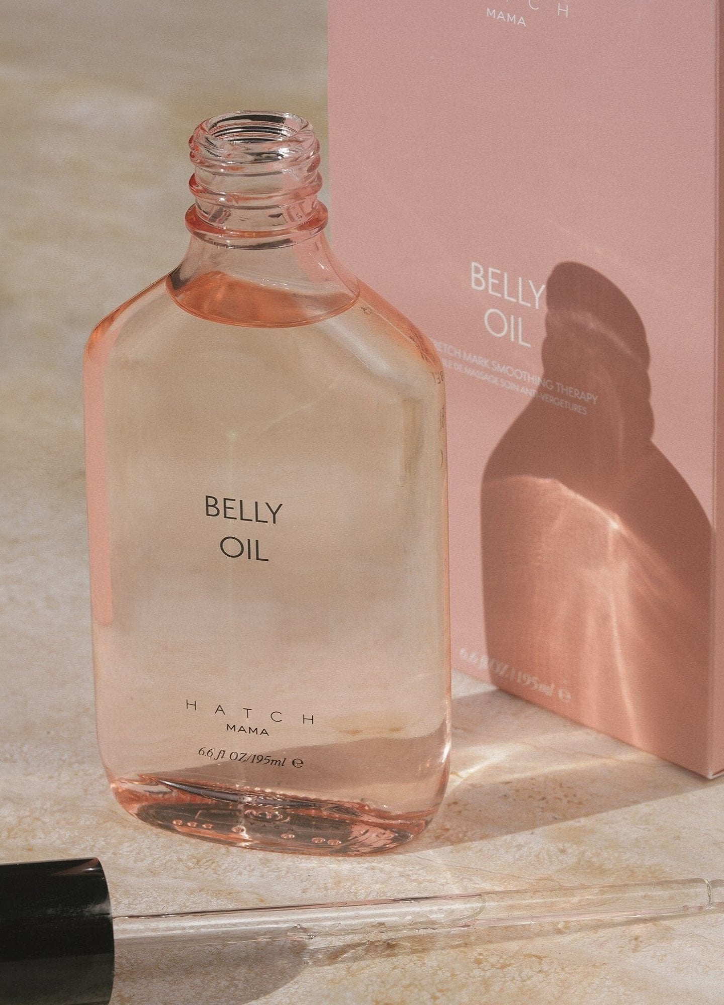 Belly Oil - Clear glass bottle of maternity belly oil with soft pink liquid, designed for pregnancy, nursing, and postpartum care next.