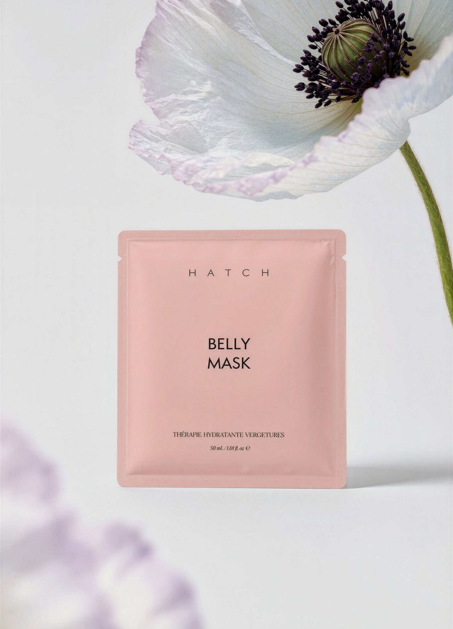 Matte pink rectangular packet labeled "Belly Mask" with soft white flower on a light background.