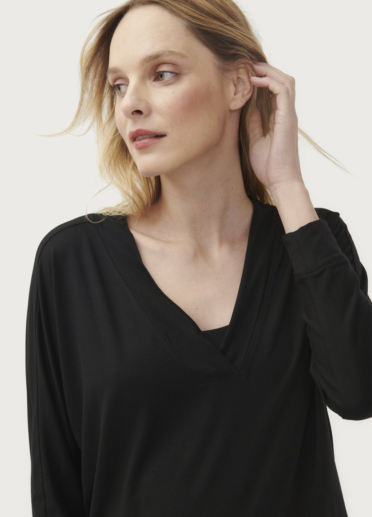 Black long-sleeve maternity top with relaxed fit and V-neckline modeled by woman.